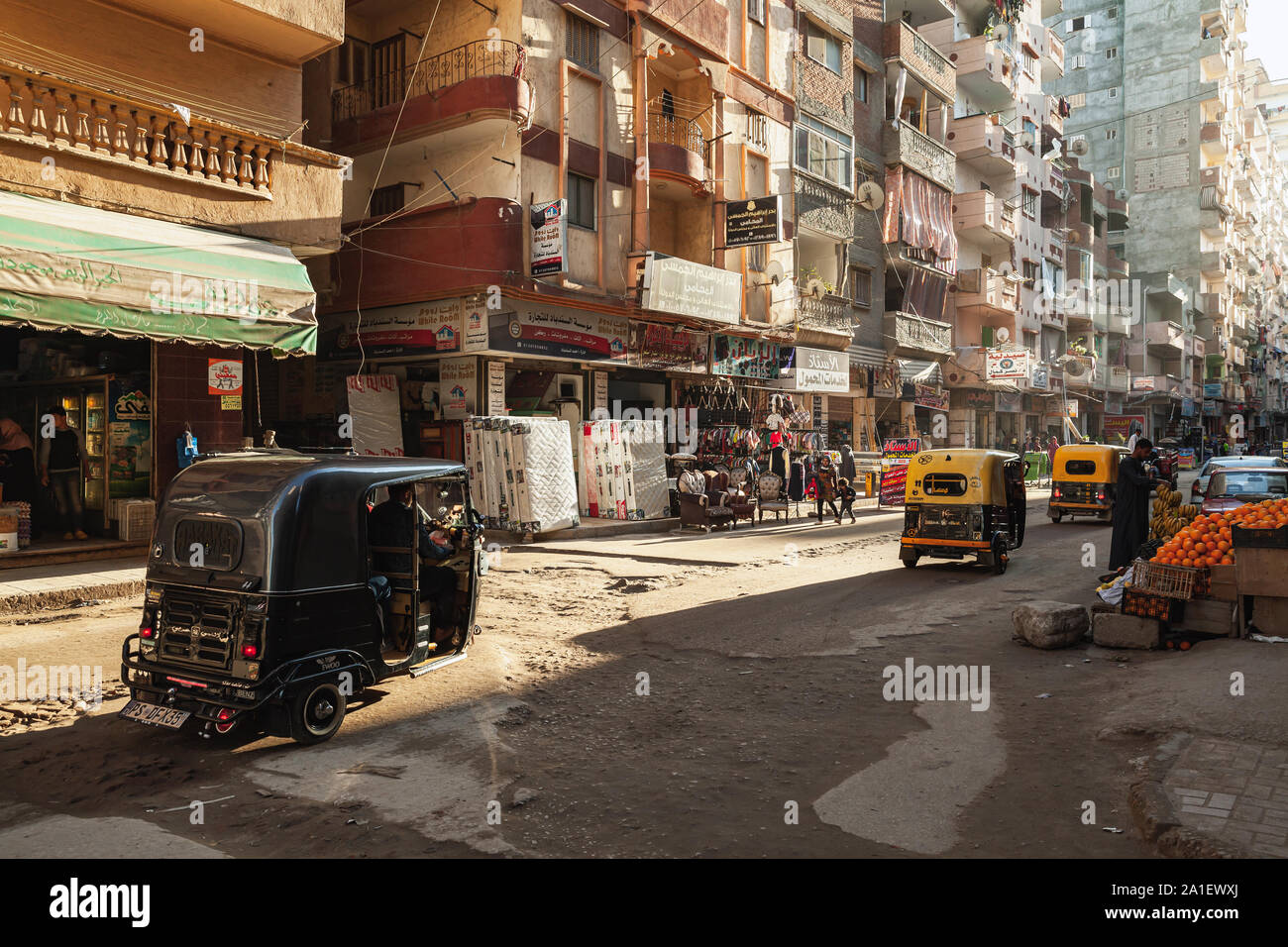 Alexandria, Egypt - December 18, 2018: Street view of Alexandria, ordinary people walk the street with auto rickshaws Stock Photo
