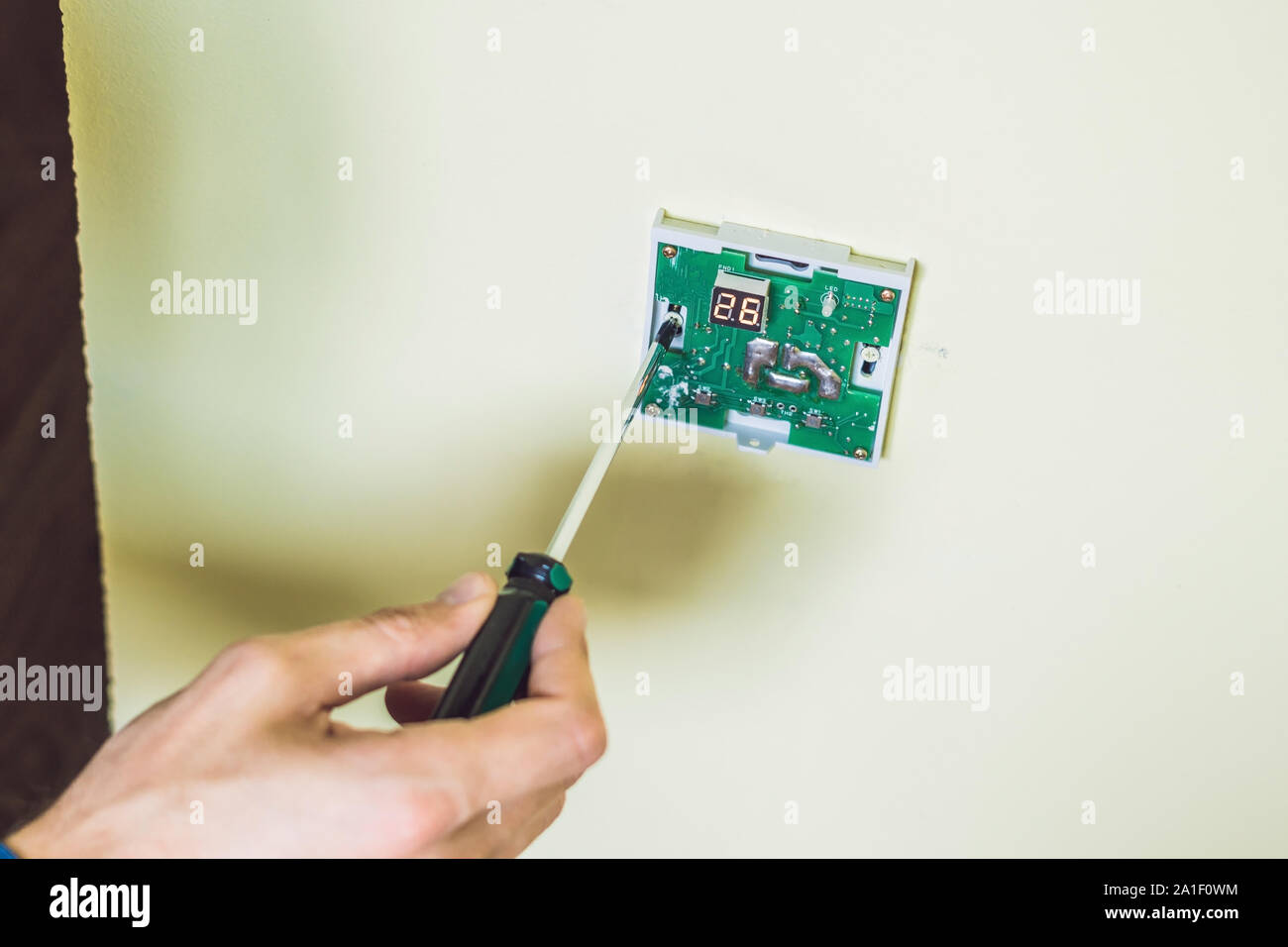 electrician installing an electrical thermostat in a new house Stock