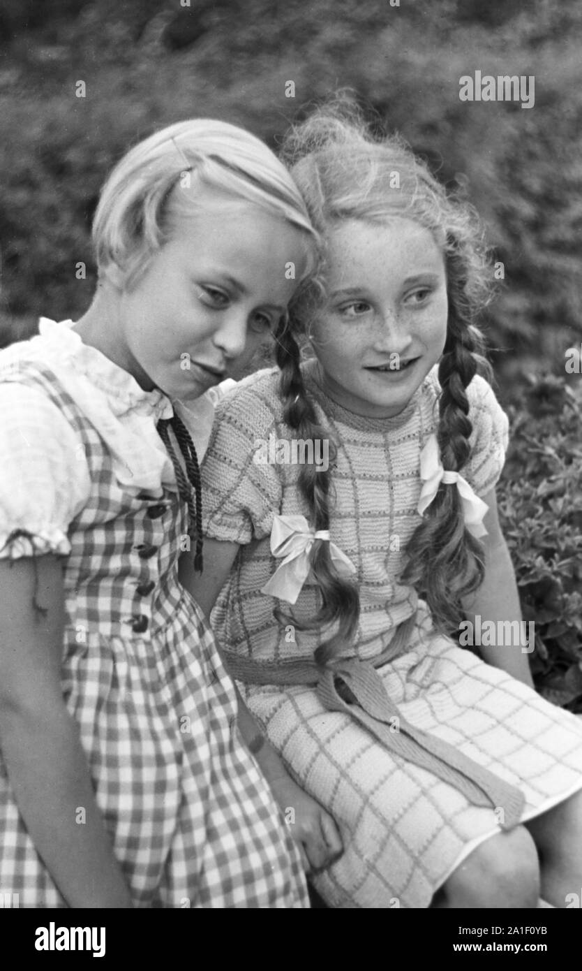 Zwei Mädchen sitzen in einem Garten, Deutschland 1939. Two girls sitting in a garden, Germany 1939. Stock Photo