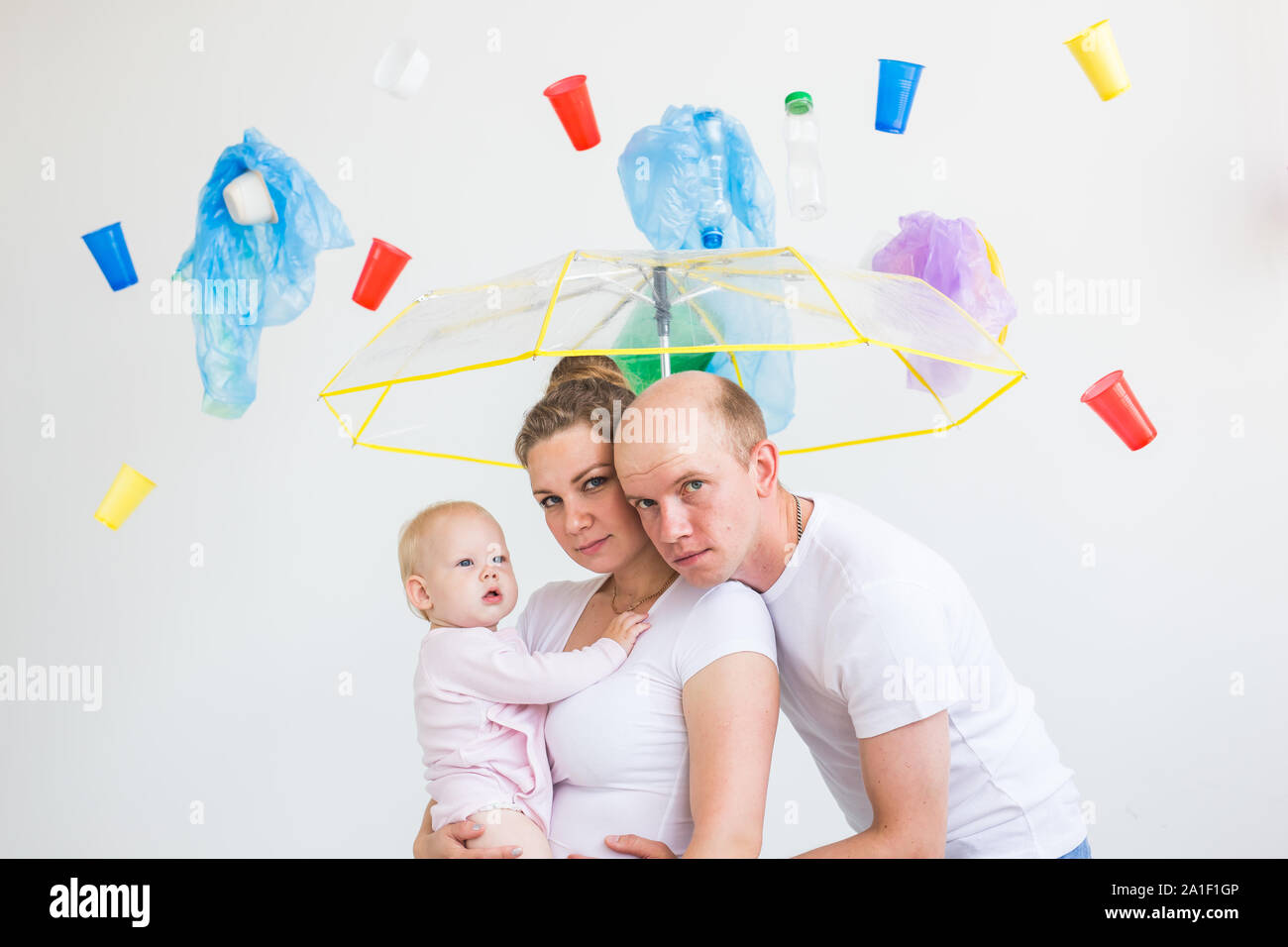 Environmental pollution, plastic recycling problem and waste disposal concept - surprised family under garbage on white background. Stock Photo