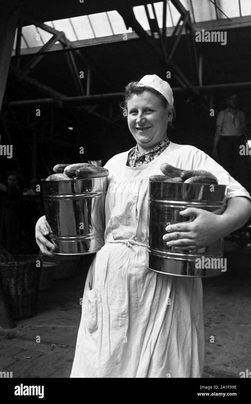Arbeiterin der Konservenfabrik C. Th. Lampe in Braunschweig mit zwei Eimern Gurken, Deutschland 1939. Worker with canned cucumbers for canning at the canning factory C. Th. Lampe in Brunswick, Germany 1939. Stock Photo