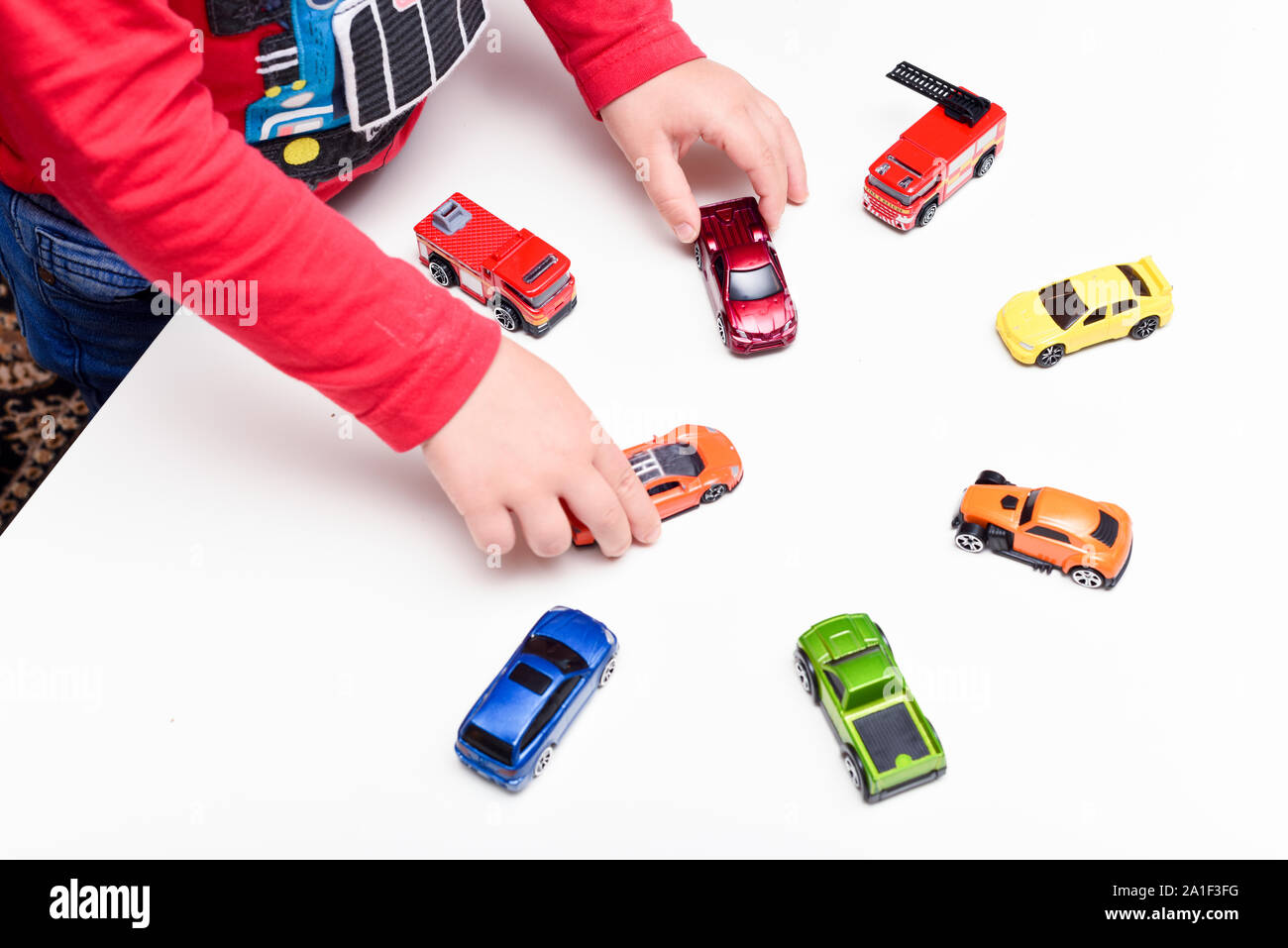 Playing at home The boy is playing with toy cars at the table Stock ...