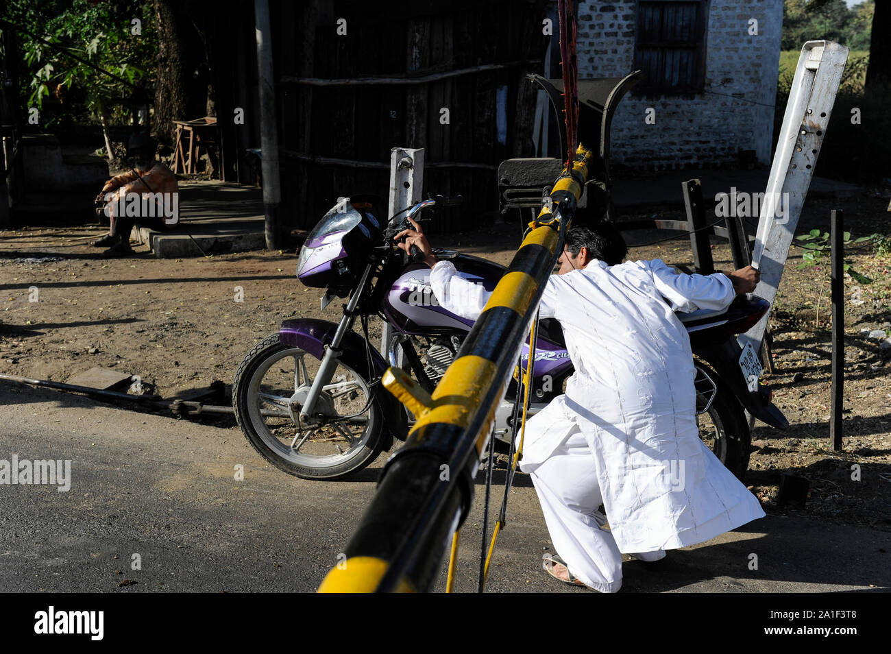 INDIA, Madhya Pradesh, Nimad region, Khargone, motorbike driver violate traffic rules while crossing a Railroad Crossing with closed barriers Stock Photo