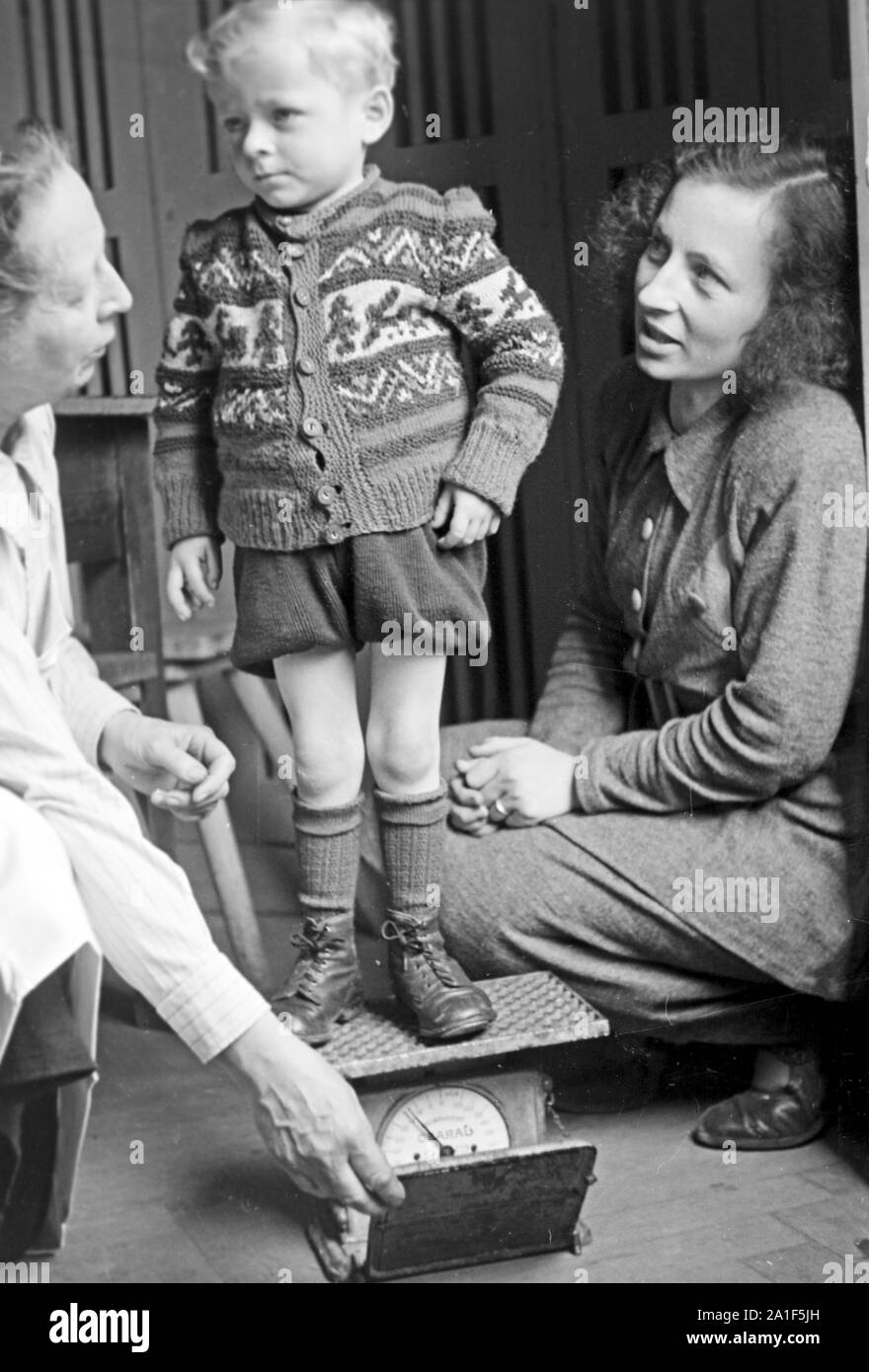 Ein Junge auf der Waage nach der Speisung durch die Canadian Lutheran World Relief in einer karitativen Einrichtung in Frankfurt an der Oder, Deutschland 1948. A boy is weighed after he got the feeding sponsored by the Canadian Lutheran World Relief at a charity station in Frankfurt / Oder, Germany 1948. Stock Photo