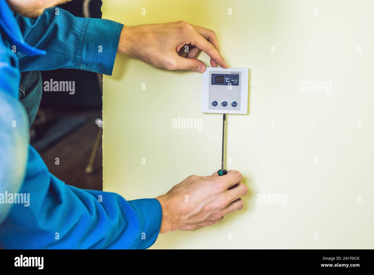 electrician installing an electrical thermostat in a new house Stock