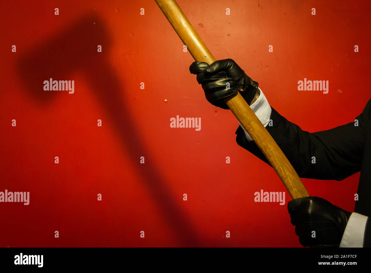 Shadow of Axe Held by Man in Dark Suit and Leather Gloves. Concept of Horror Movie Murderer. Dark Stock Photo. Stock Photo