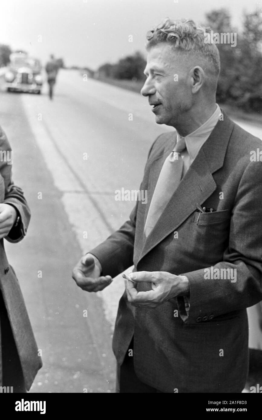 Mann raucht am Strassenrand, Schleswig-Holstein, Deutschland, 1960er Jahre. Man smoking on the roadside, Schleswig-Holstein, Germany, 1960s. Stock Photo