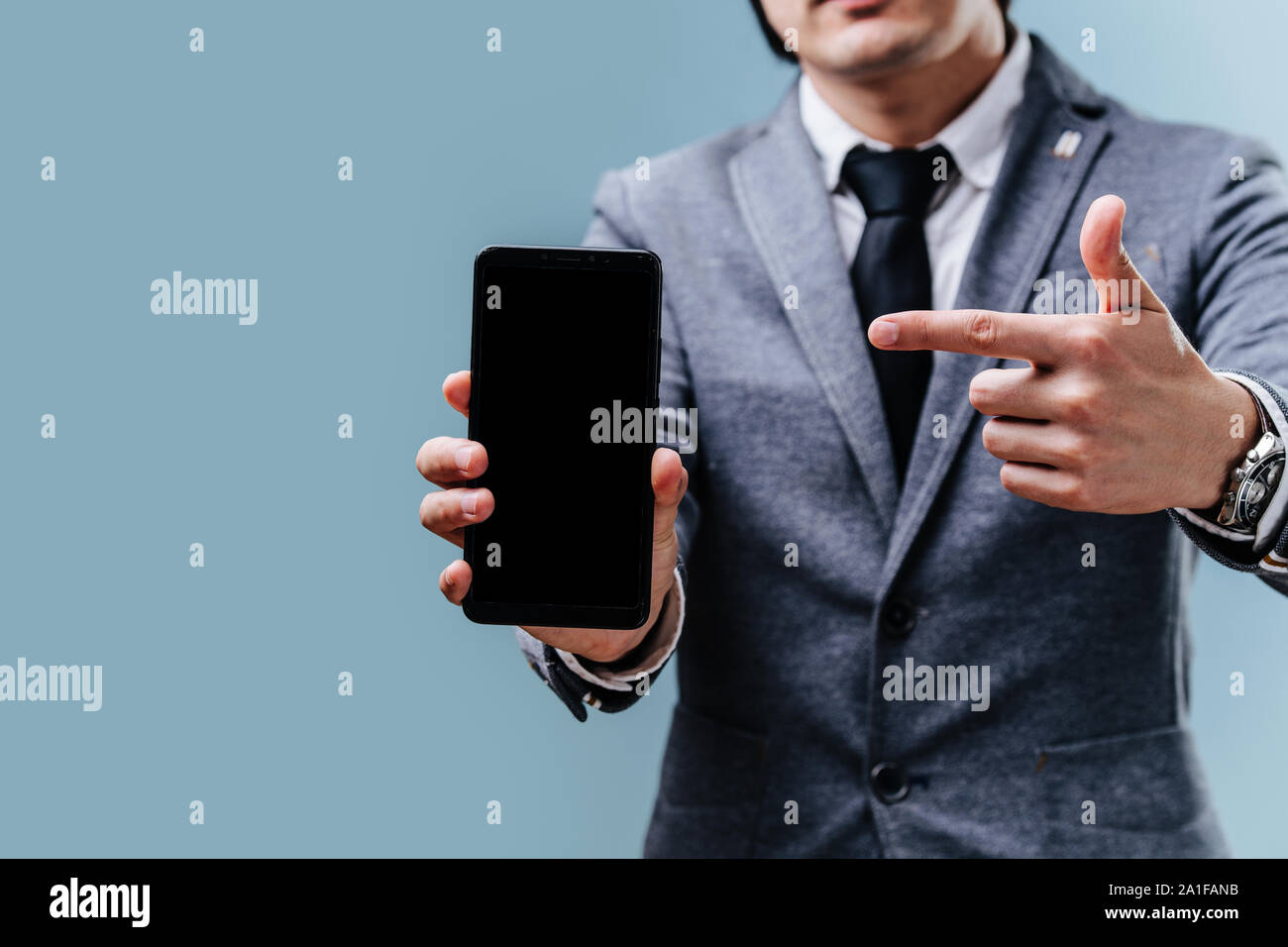 Businessman is pointing on his smartphone with index finger over blue background Stock Photo