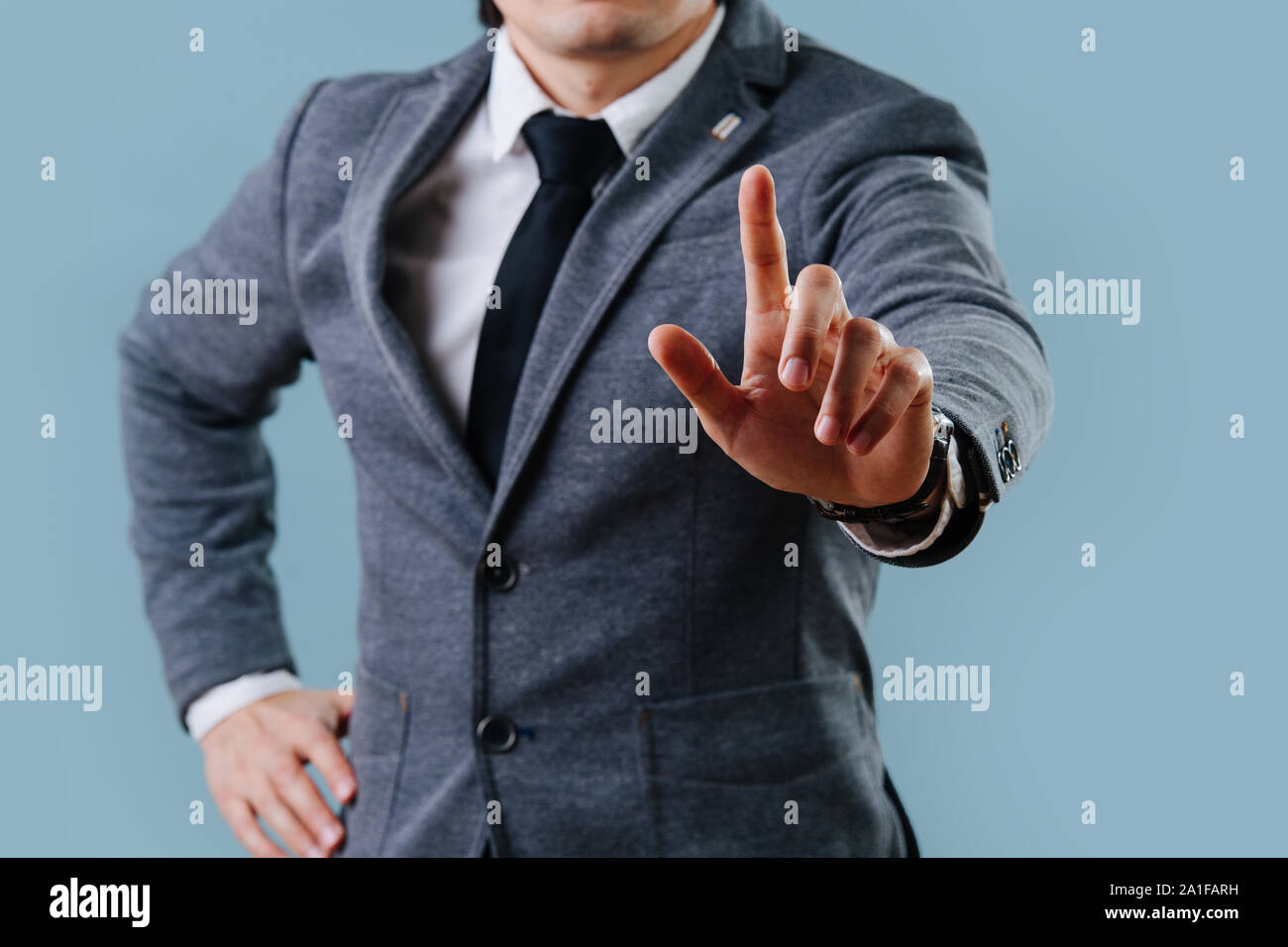 Businessman in suit making objection gesture , holding index finger up over blue Stock Photo
