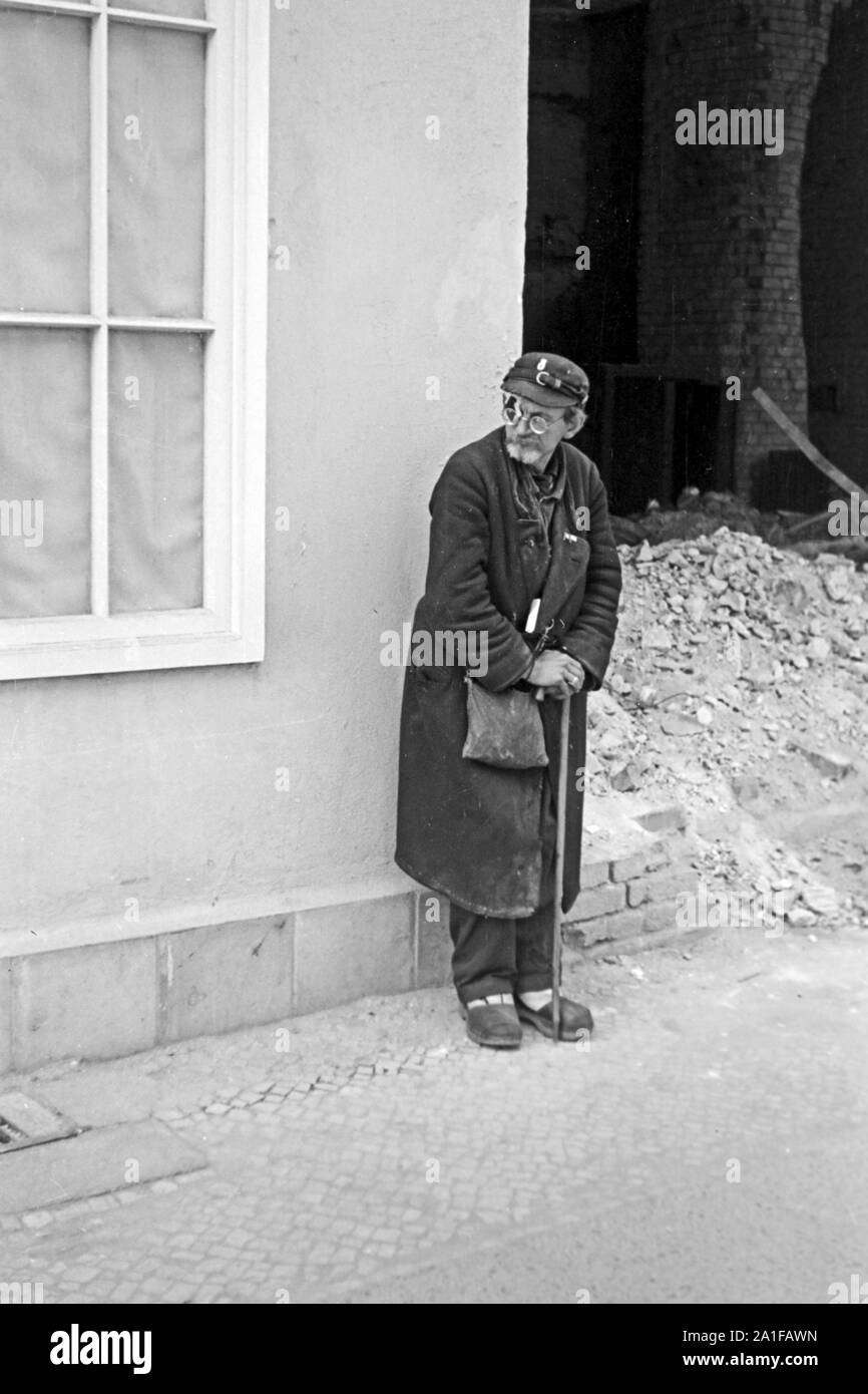 Ein Kriegsversehrter lehnt an einer Hauswand in Berlin, Deutschland 1949. A war invalid standing at a wall in Berlin, Germany 1949. Stock Photo