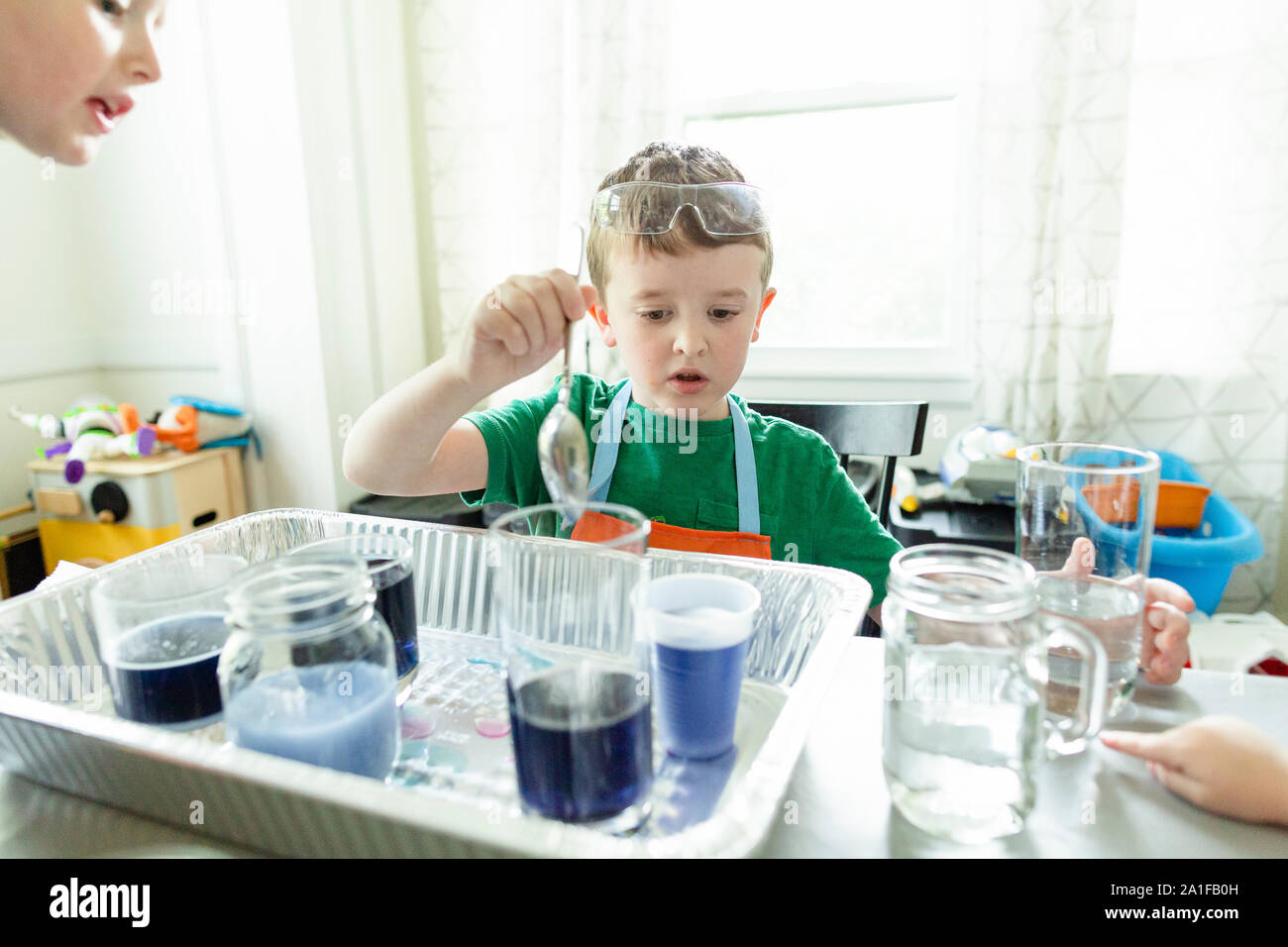 Elementary age boy focused doing chemistry science experiment at home Stock Photo