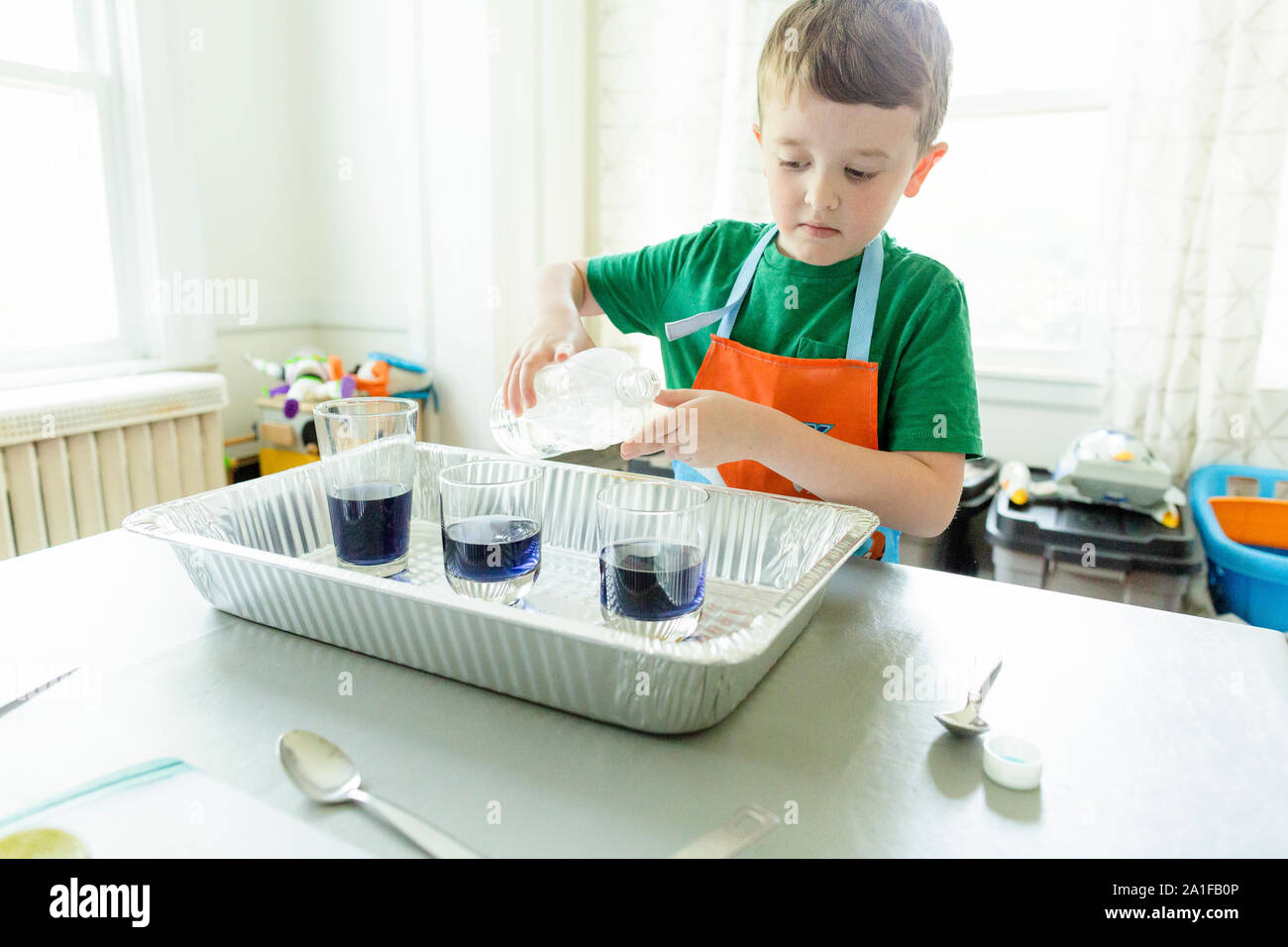 Elementary age male student pours liquid during science experiment