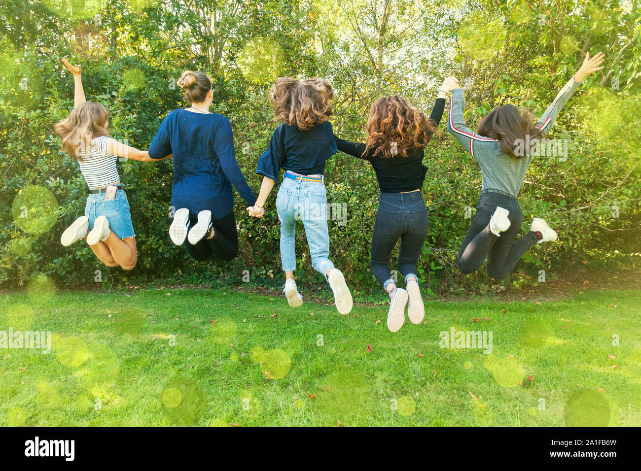group of teenagers girls jumping in a park in summertime. Having fun in holidays. Happy friends spending time together. Friendship. diversity. unity Stock Photo