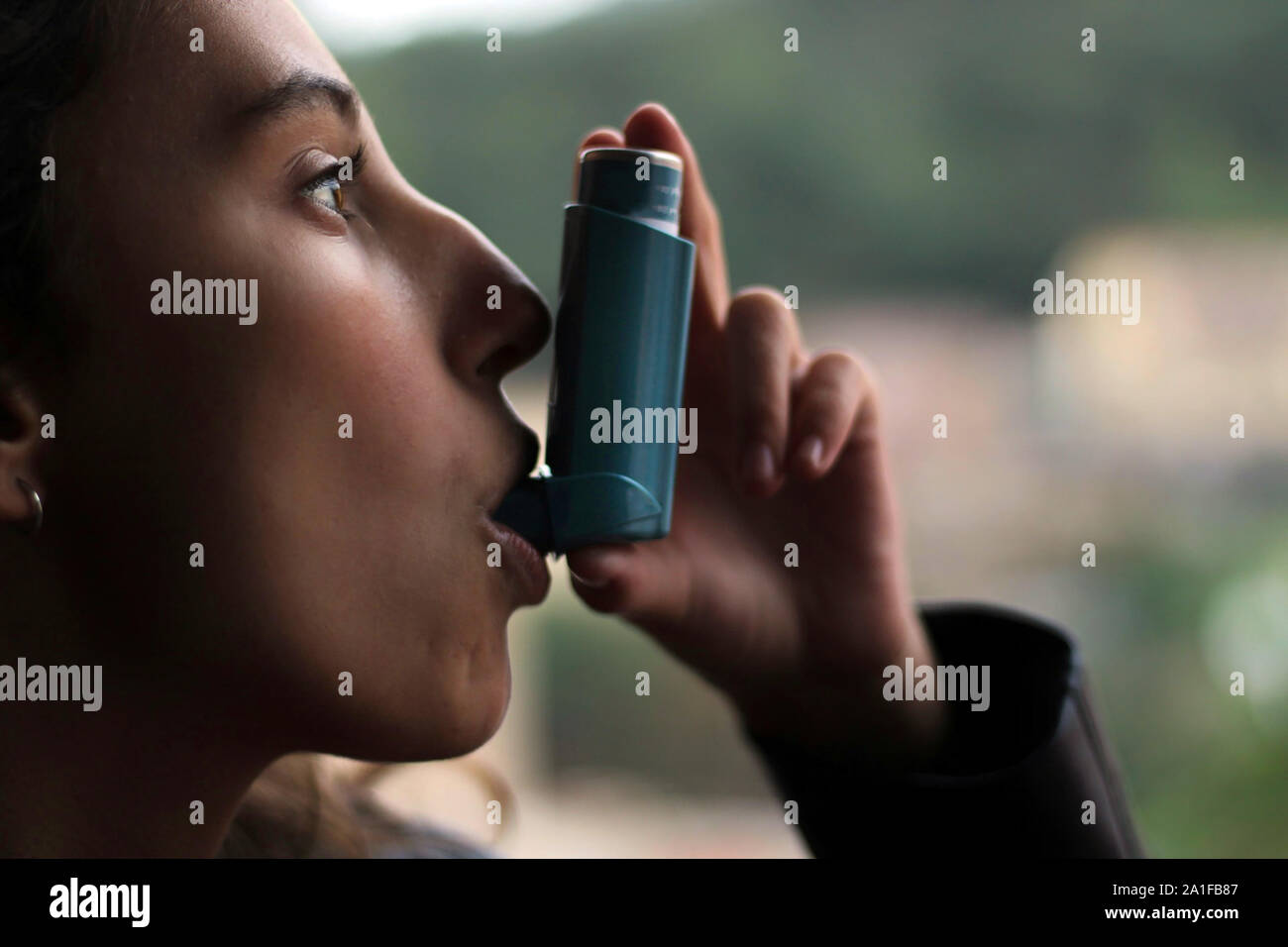 Health and medicine - Young girl using blue asthma inhaler to prevent an asthma attack. Pharmaceutical product to prevent and treat asthma. Stock Photo
