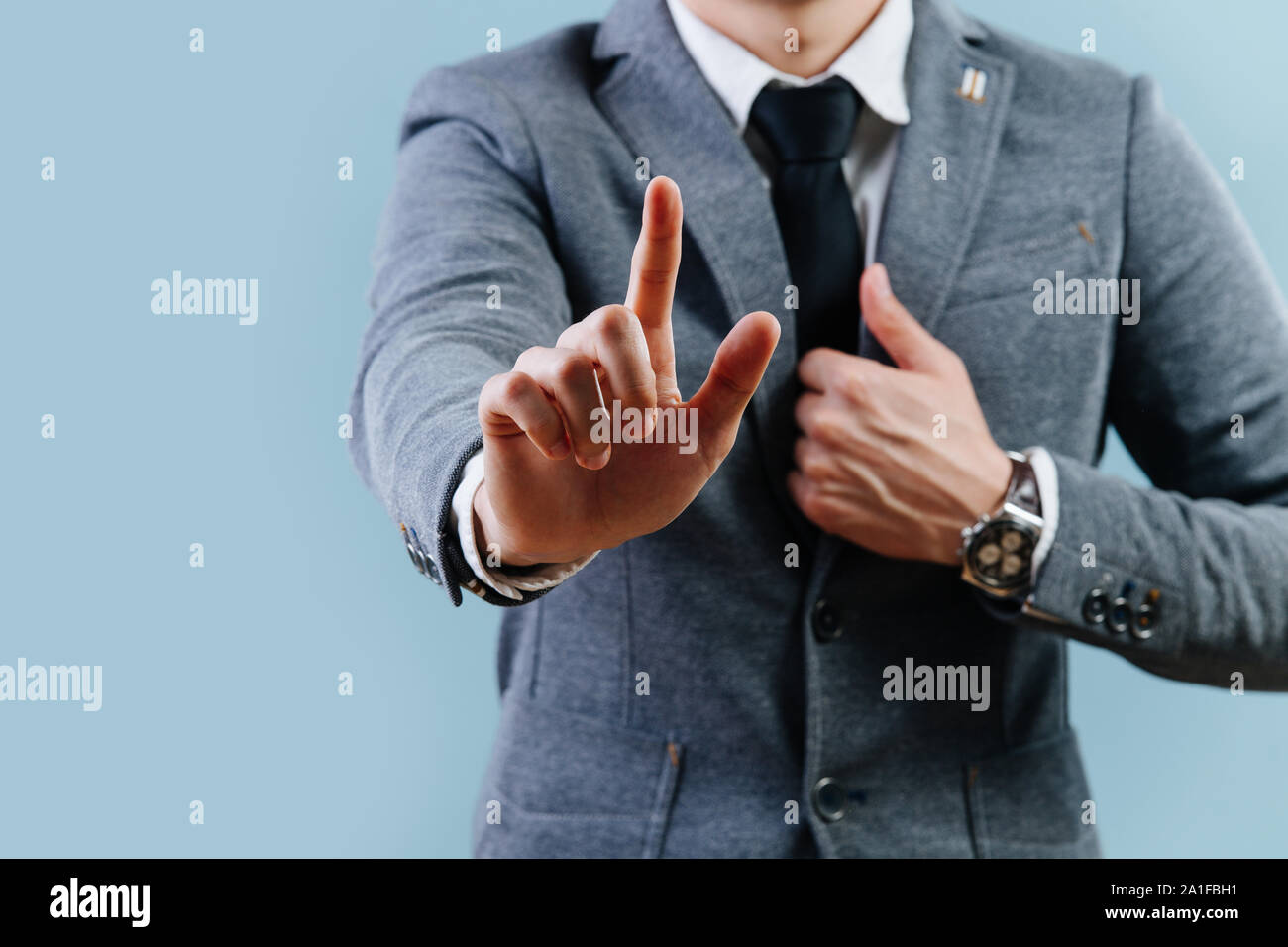 Businessman in suit making objection gesture , holding index finger up over blue Stock Photo