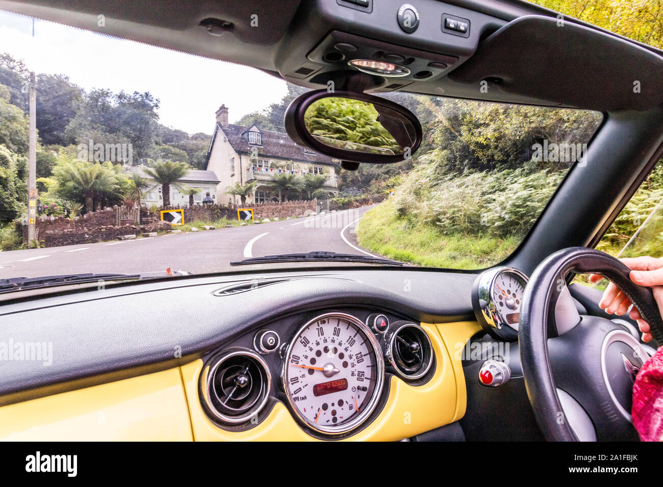 Passenger's view of a yellow convertible Mini Cooper going up Porlock Hill, Somerset UK Stock Photo