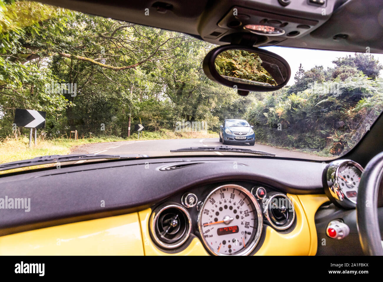 Passenger's view of a yellow convertible Mini Cooper going up Porlock Hill, Somerset UK Stock Photo