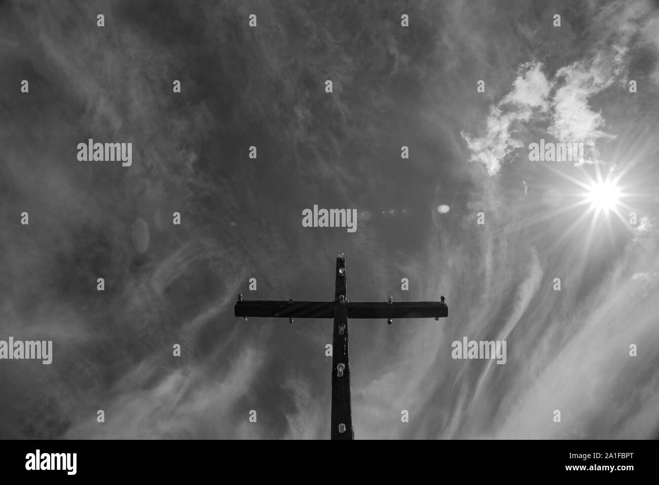 Low angle view of holy cross under the sun, clouds and sky Stock Photo