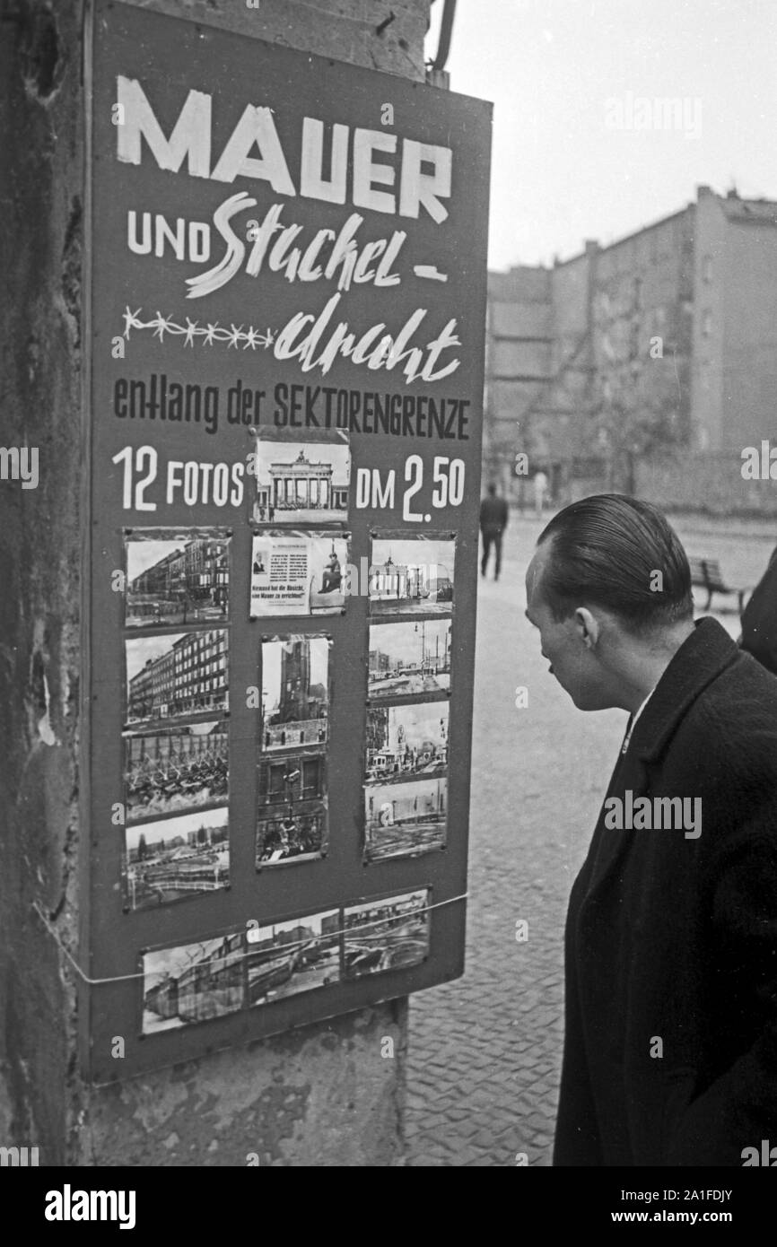 Touristen interessieren sich für ein Set von 12 Fotos 'Mauer und Stacheldraht' in Berlin, Deutschland 1962. Tourists interested in a photo set titled 'Wall and barbed wire' at a souvenir shop in Berlin, Germany 1962. Stock Photo