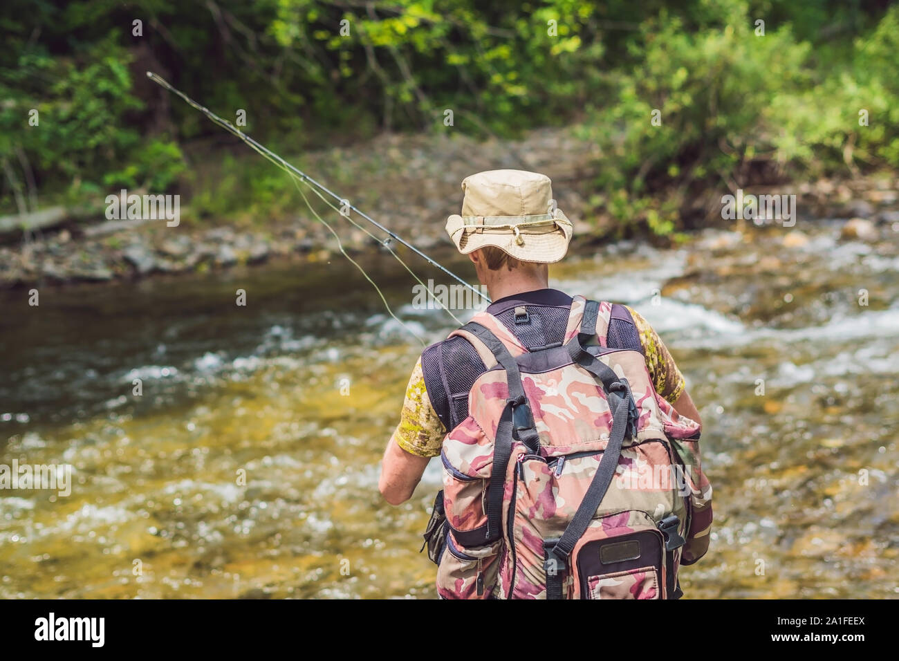 Man fishing on a mountain river with a ultralight spinning using fishing  wobblers. He got his hook hooked for something Stock Photo - Alamy
