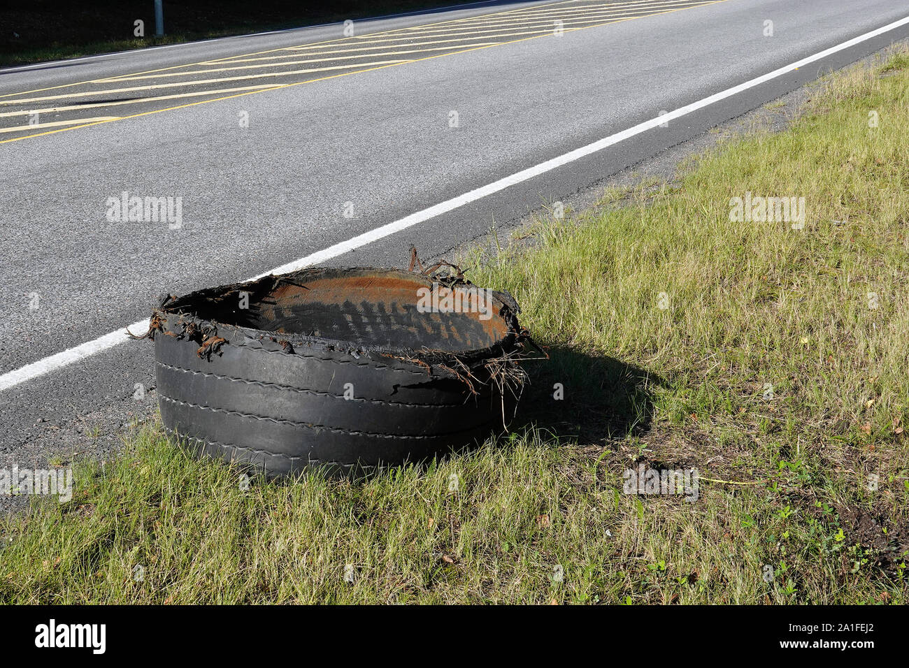 Exploded tire of semi truck on highway roadside. Stock Photo