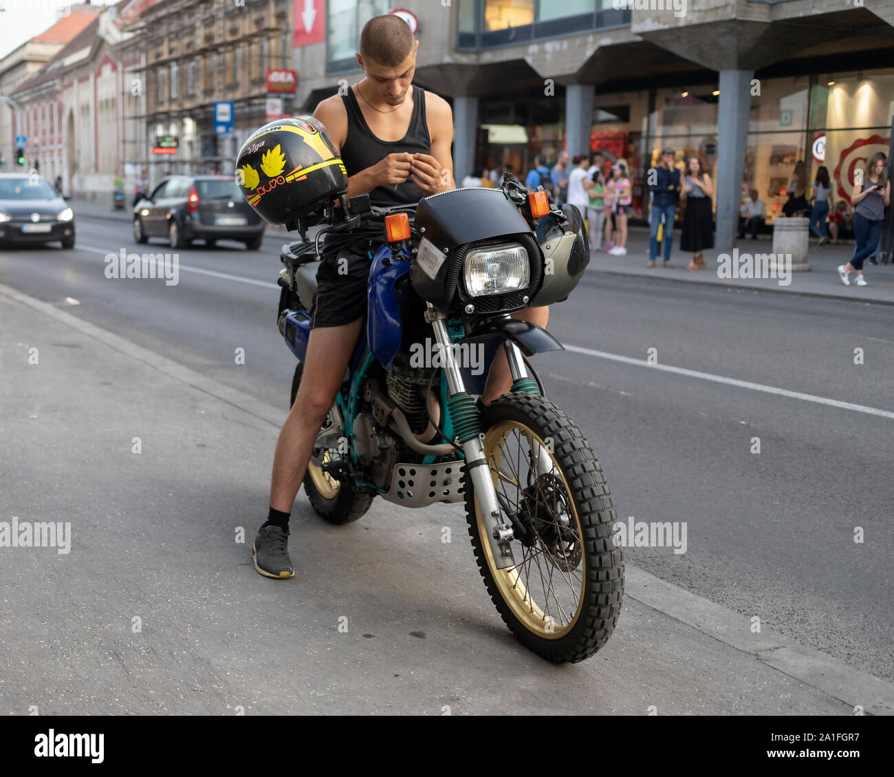 Belgrade, Serbia Aug 29, 2019: Urban scene with a young man sitting on a motorbike parked at a sidewalk Stock Photo