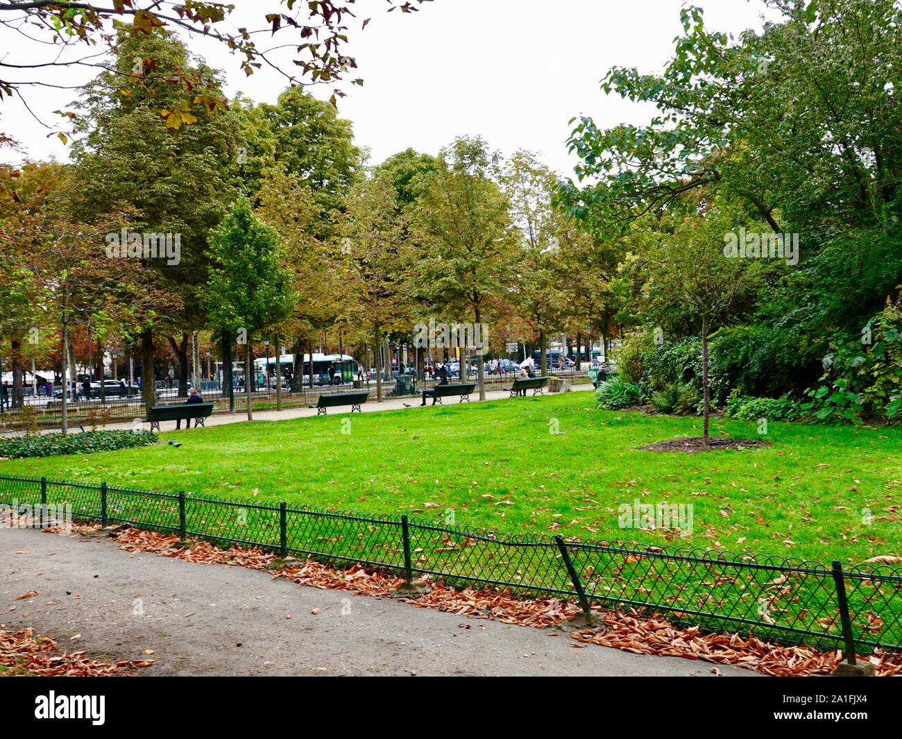 People sitting on green benches in a public park, and background