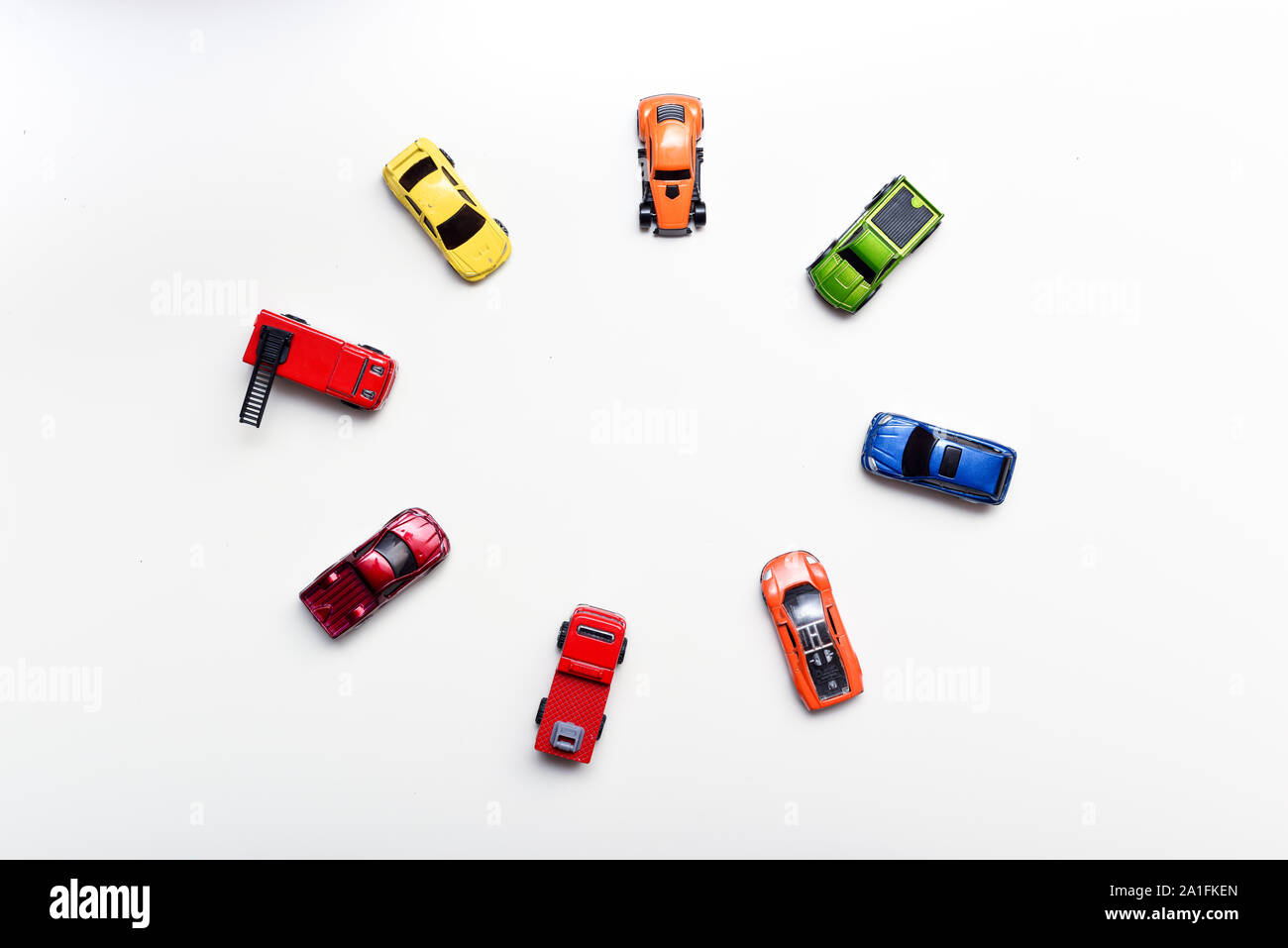 Overhead shot of child's toy cars arranged on a white table, no people in shot Stock Photo