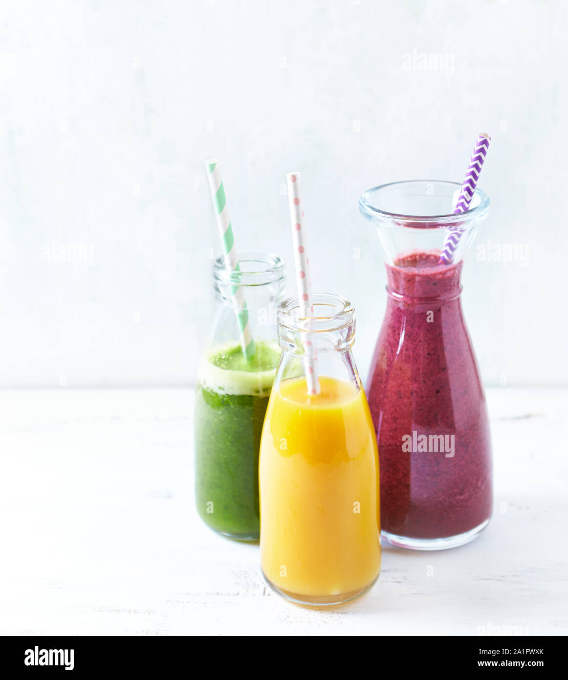Colorful vegan smoothies with raspbeerries, blueberries, banana, pineapple, mango, arugula, spinach and apple. Stock Photo