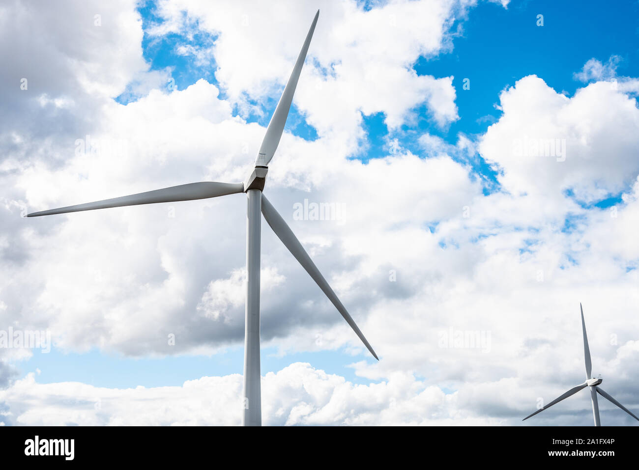 Wind turbines against a cloudy sky with patches of blue. Copy space. Stock Photo