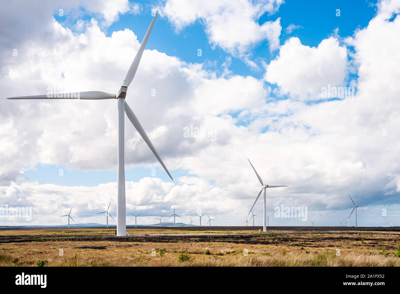 Wind turbine for electricity generation in a field on a partly cloudy spring day Stock Photo