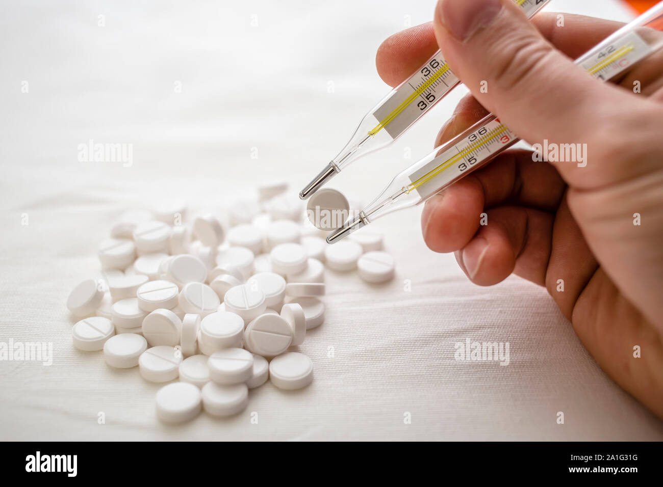 man is going to eat the drug tablets and holds two medical thermometer like chopsticks Stock Photo