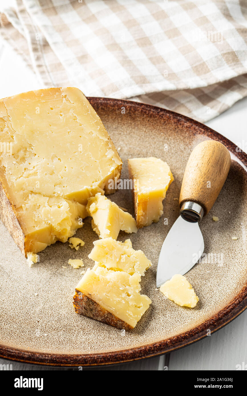 Crushed block of cheese and cheese knife on plate. Stock Photo