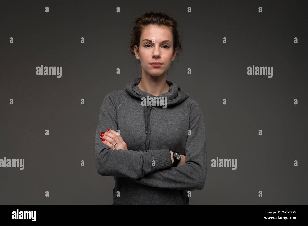 Portrait of young woman in grey hoodie against gloomy backdrop isolated Stock Photo