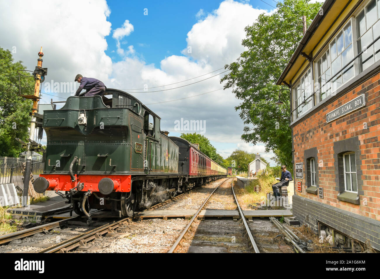 CRANMORE, ENGLAND - JULY 2019: Steam engine fireman climbing on the coal tender of the locomotive at Cranmore Station on the East Somerset Railway. Stock Photo