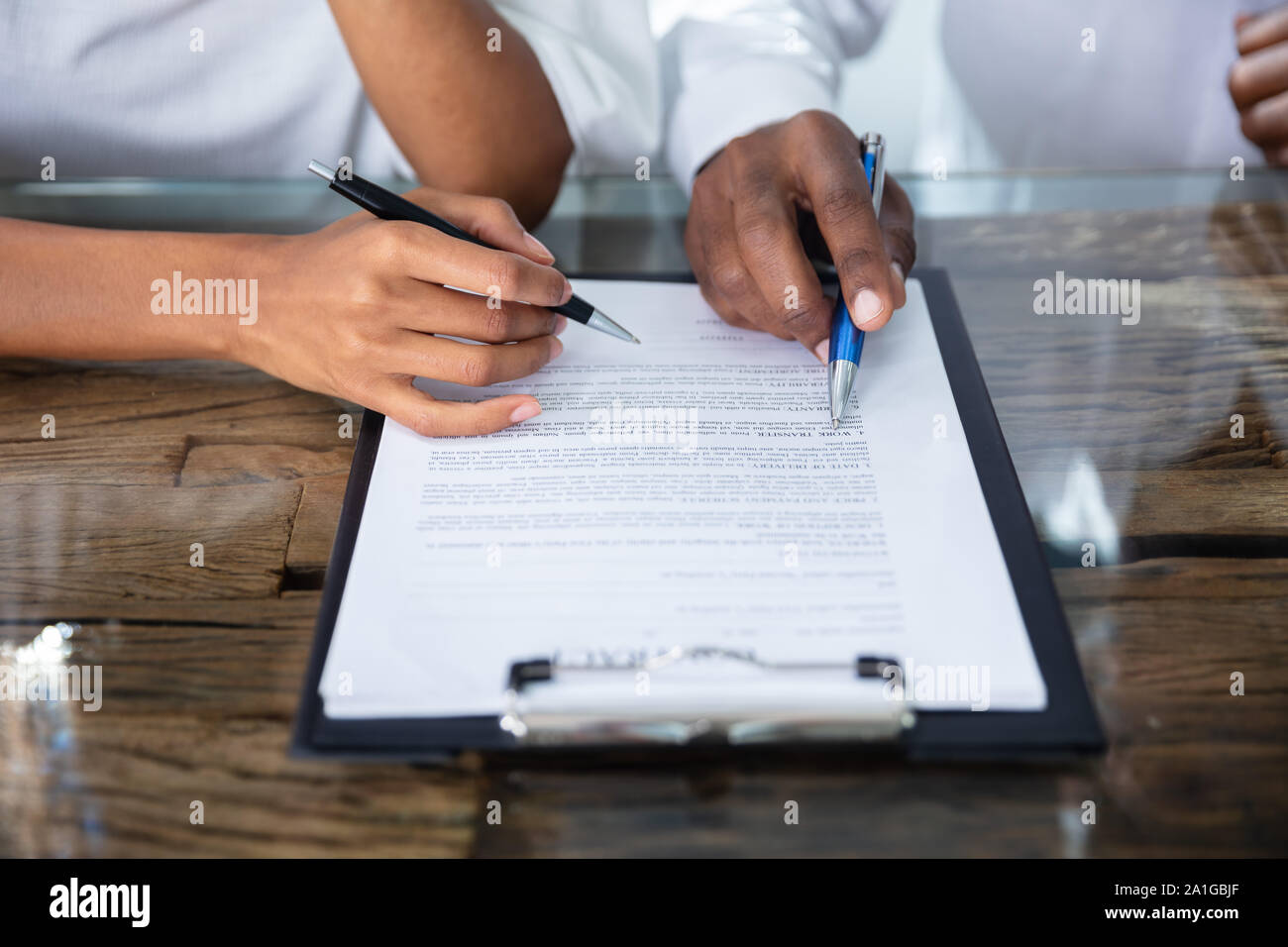 Close-up Of A Two Person's Hands Reviewing Contract Form Stock Photo