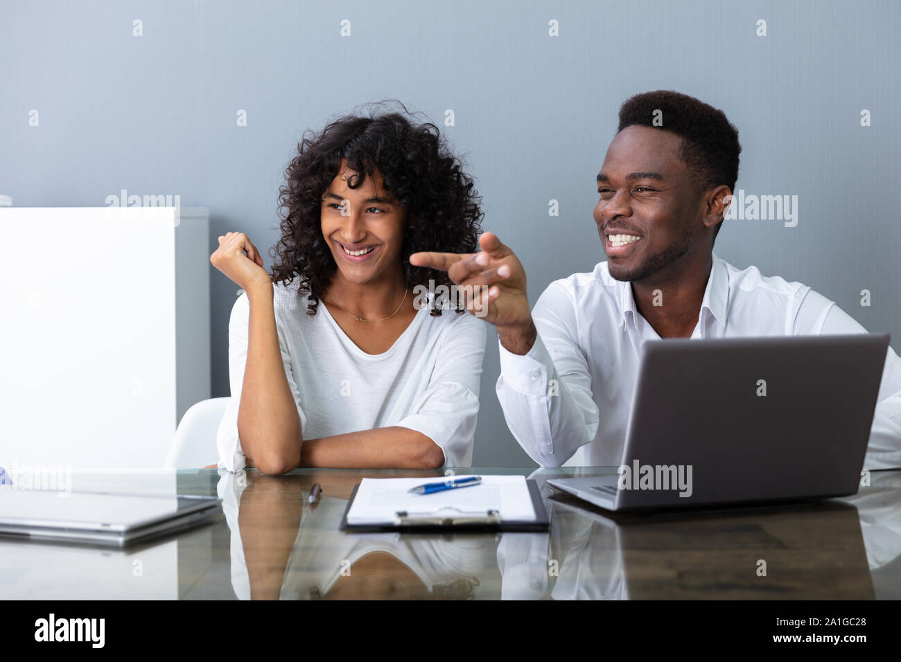 People Laughing About Their Coworker In Office Stock Photo
