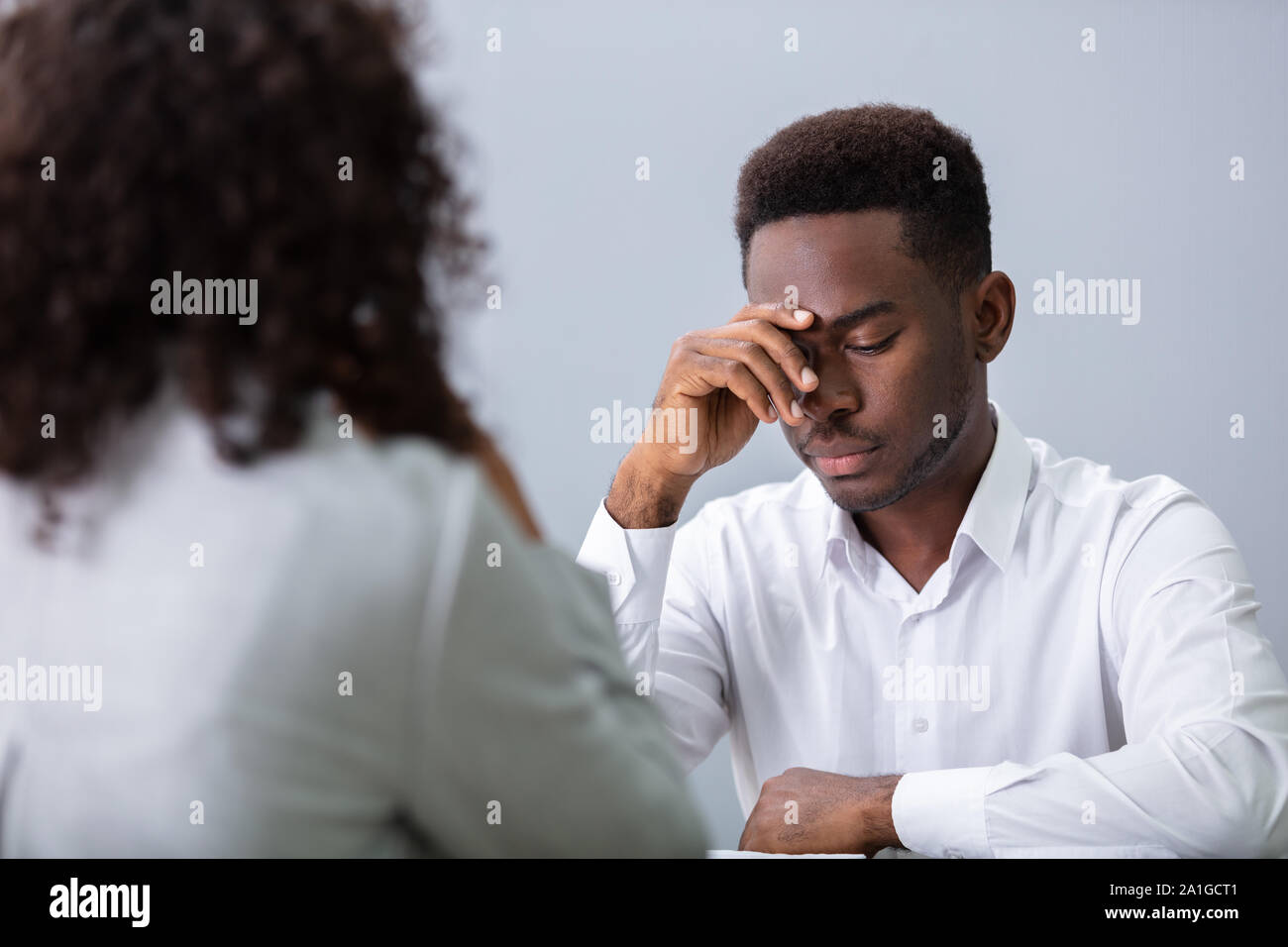 Stressed Young Business Man Holding His Head At Interview In Office Stock Photo