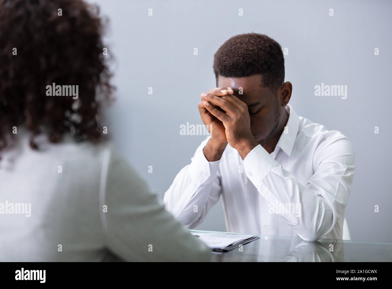 Stressed Young Business Man Holding His Head At Interview In Office Stock Photo