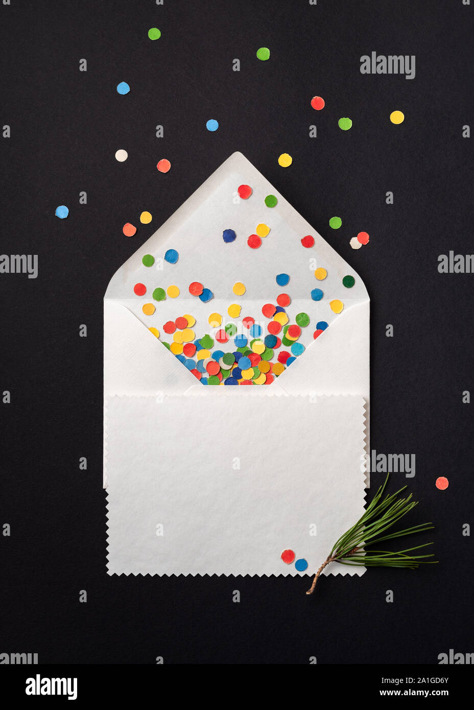 Christmas gift card on white envelope with festive confetti. Note paper sheet on black background Stock Photo