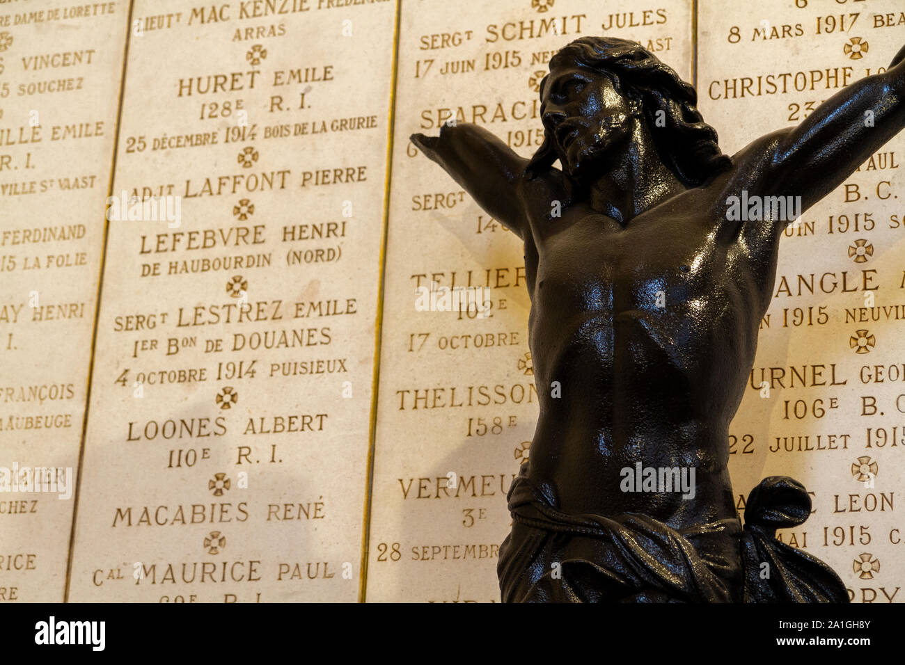 Plaques with names of soldiers fallen in WW I. Broken statue of Jesus in front of them. Church of Notre-Dame-de-Lorette at memorial of WW I (1914-18). Stock Photo