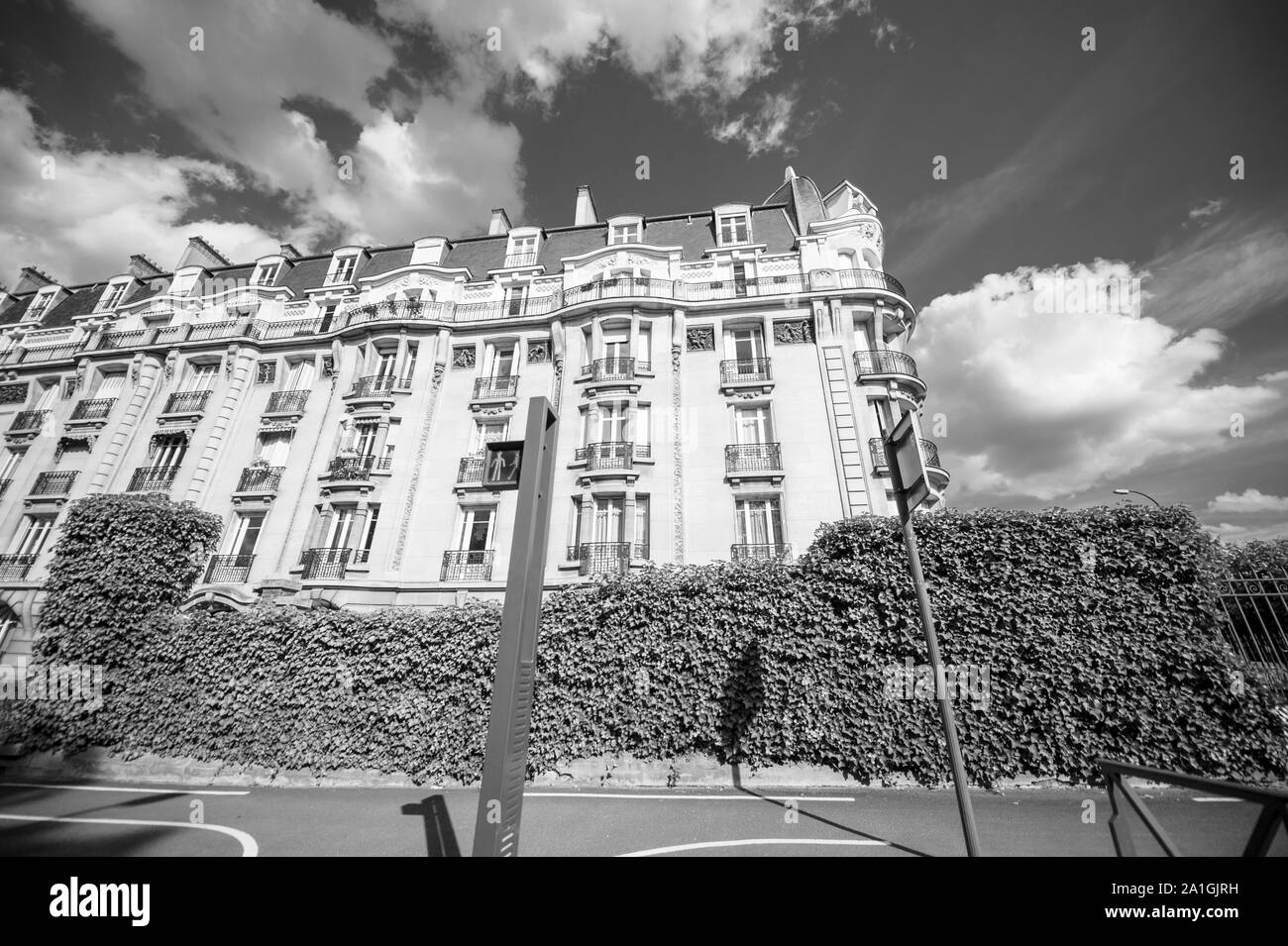 Black and white image of low wide angle view of Parisian property apartment building with French balconies and clear sky with some scattered clouds Stock Photo