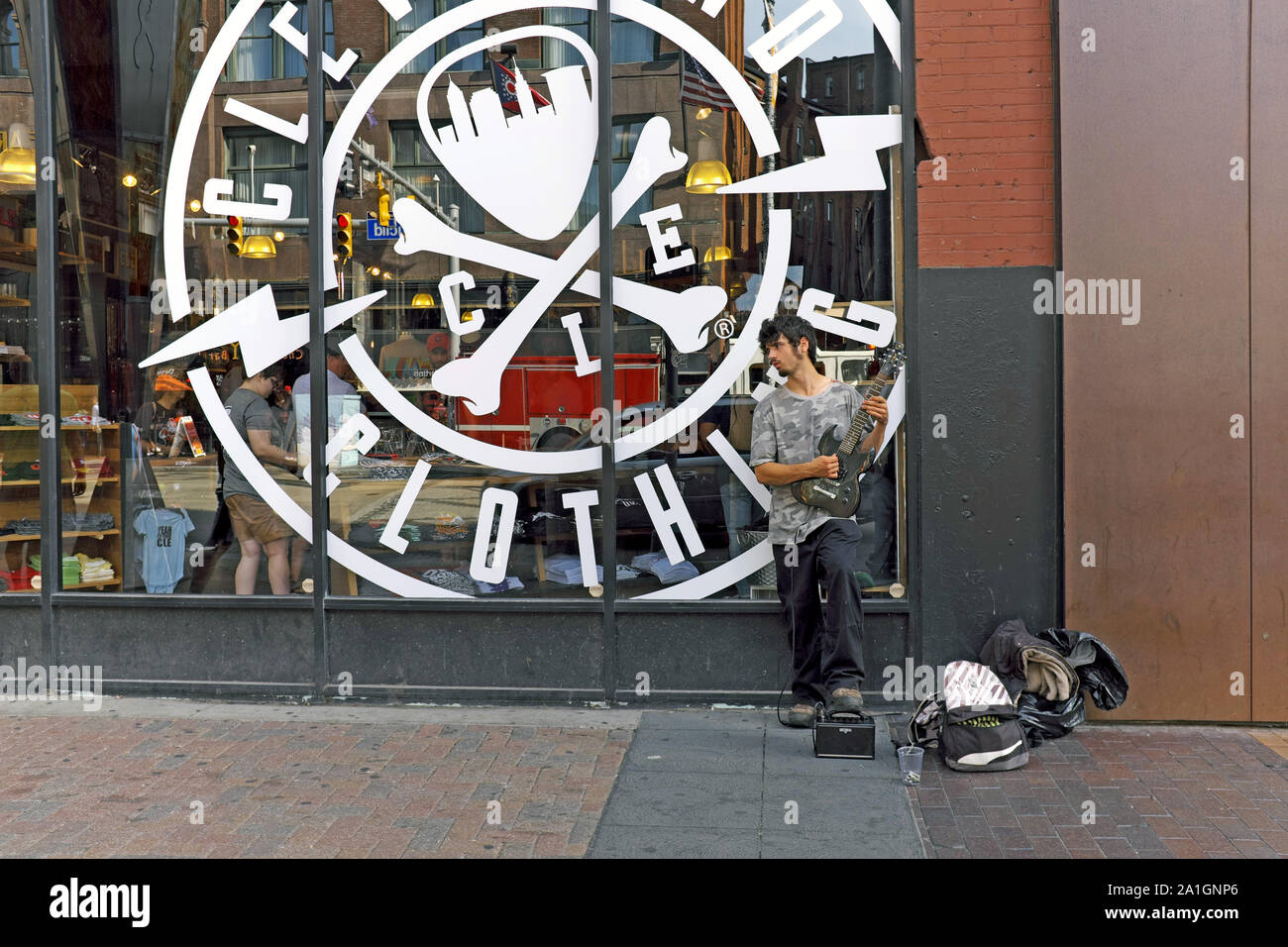 Street busker plays electric guitar on the sidewalk outside the Cleveland Clothing Company on