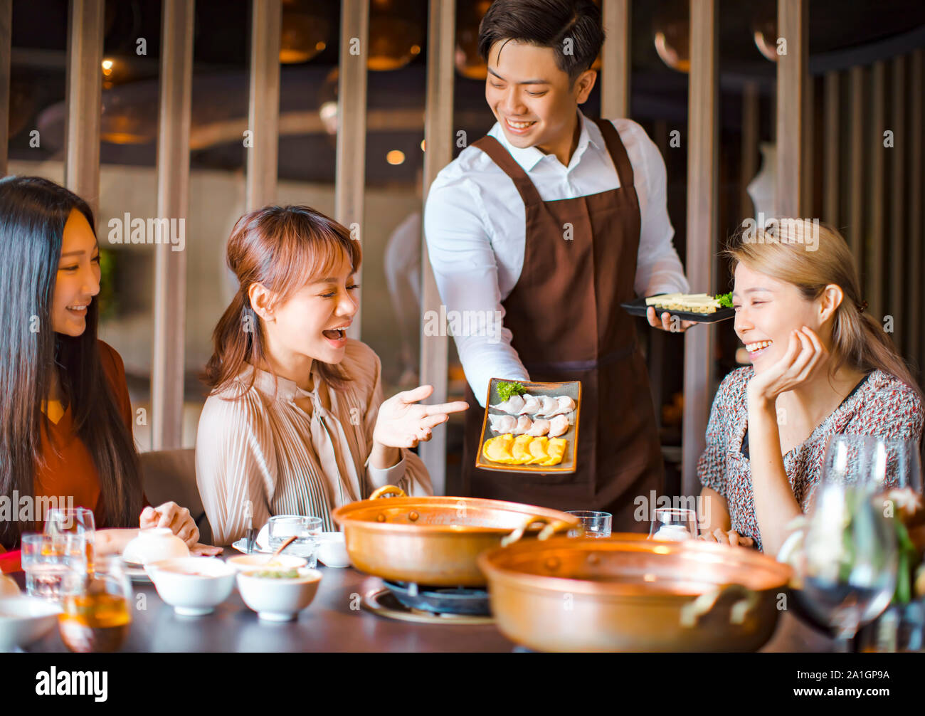 waiter  bring  egg dumpling for hot pot  and serving group of friends in restaurant Stock Photo