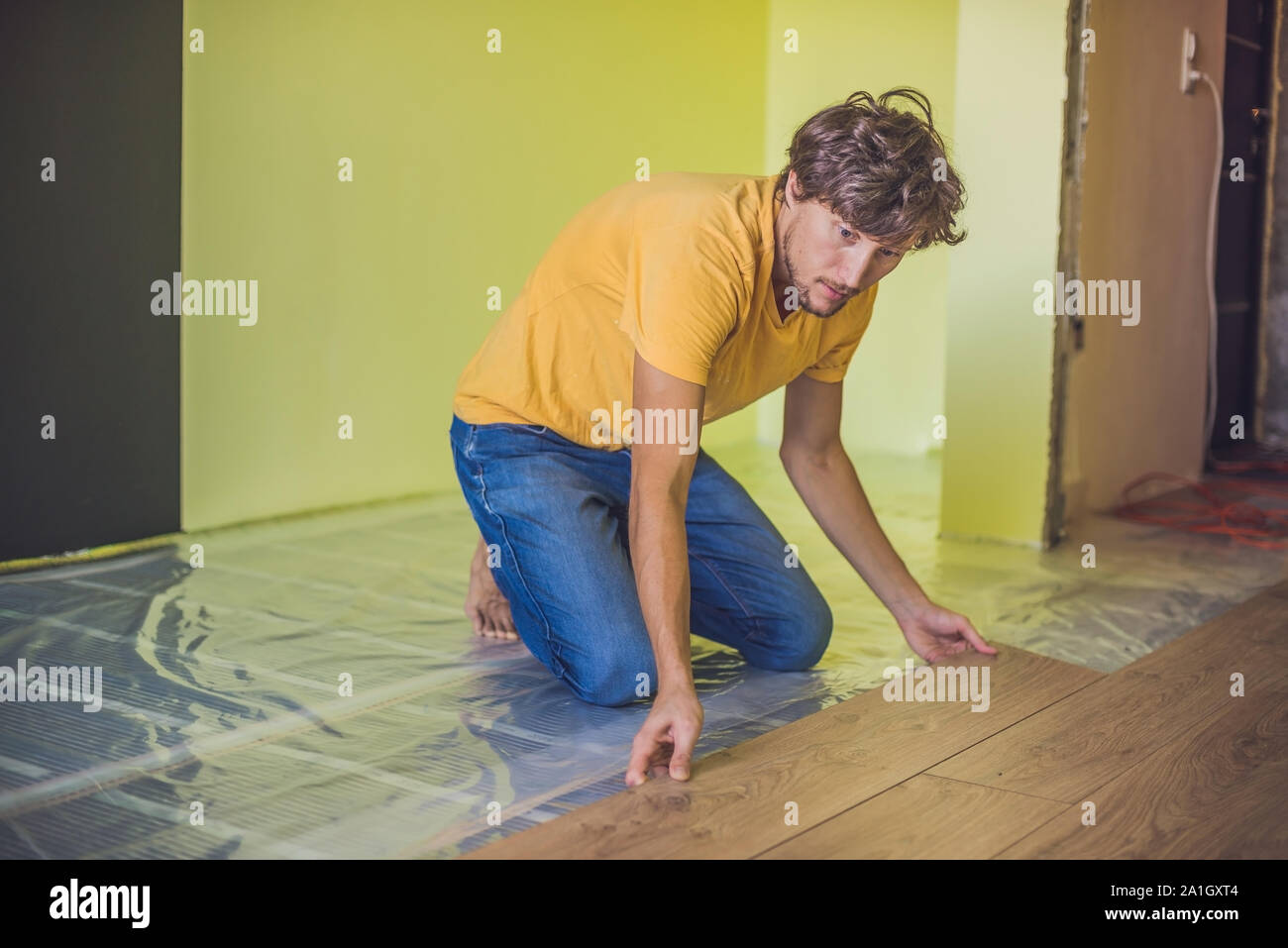 Man installing new wooden laminate flooring on a warm film floor