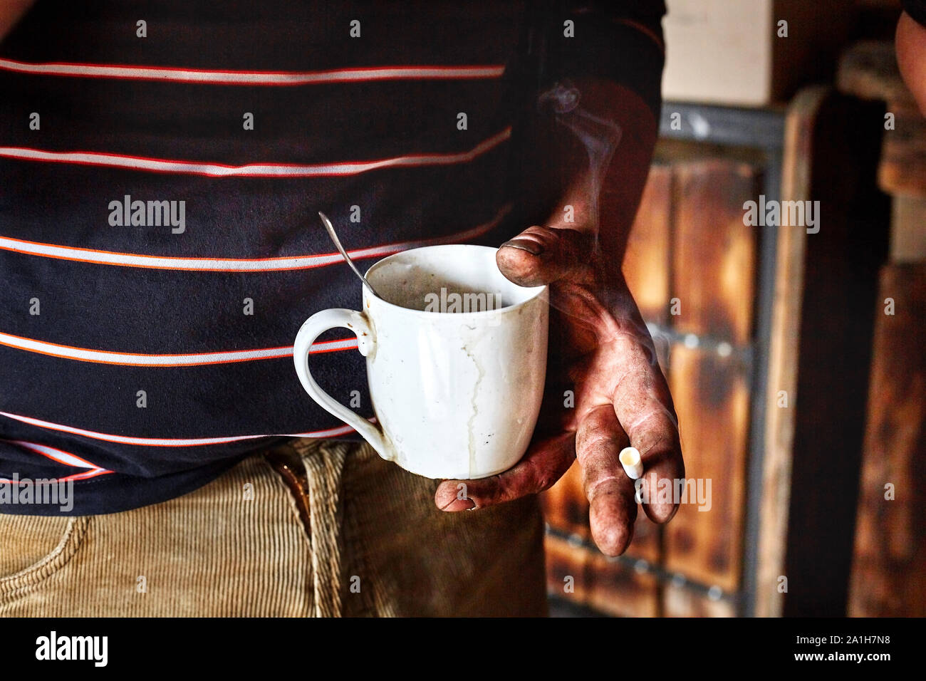 dirty hand holding a Cup with a drink and a cigarette. Stock Photo