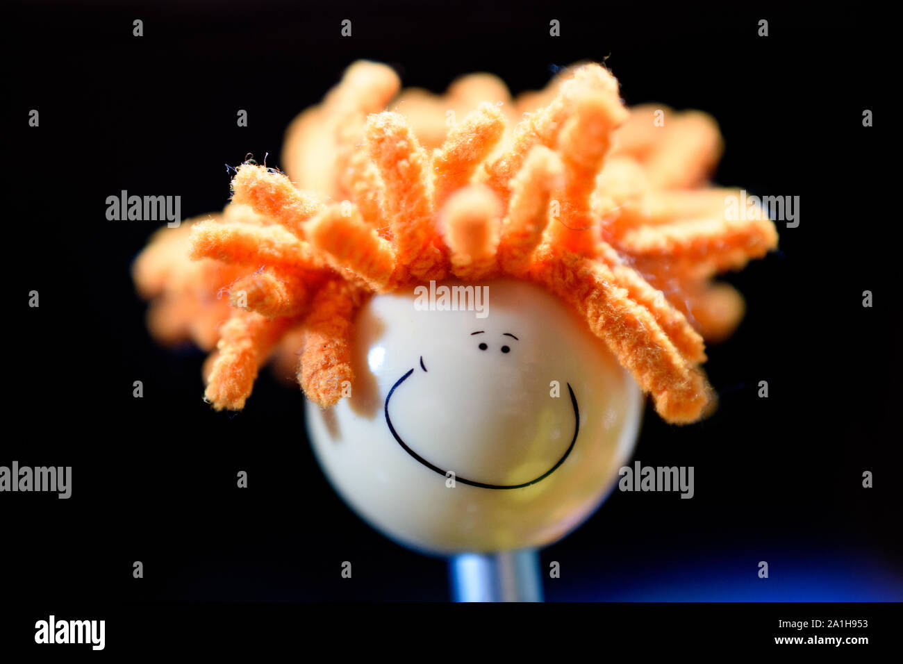 Closeup of Adorable Novelty Pen Top Smiley Face with Orange Yarn Dreadlocks Stock Photo