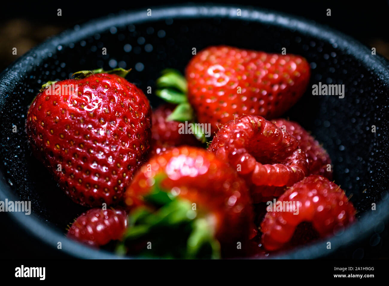 Closeup of Bowl of Mixed Juicy Red Ripe Strawberries and Raspberries Stock Photo