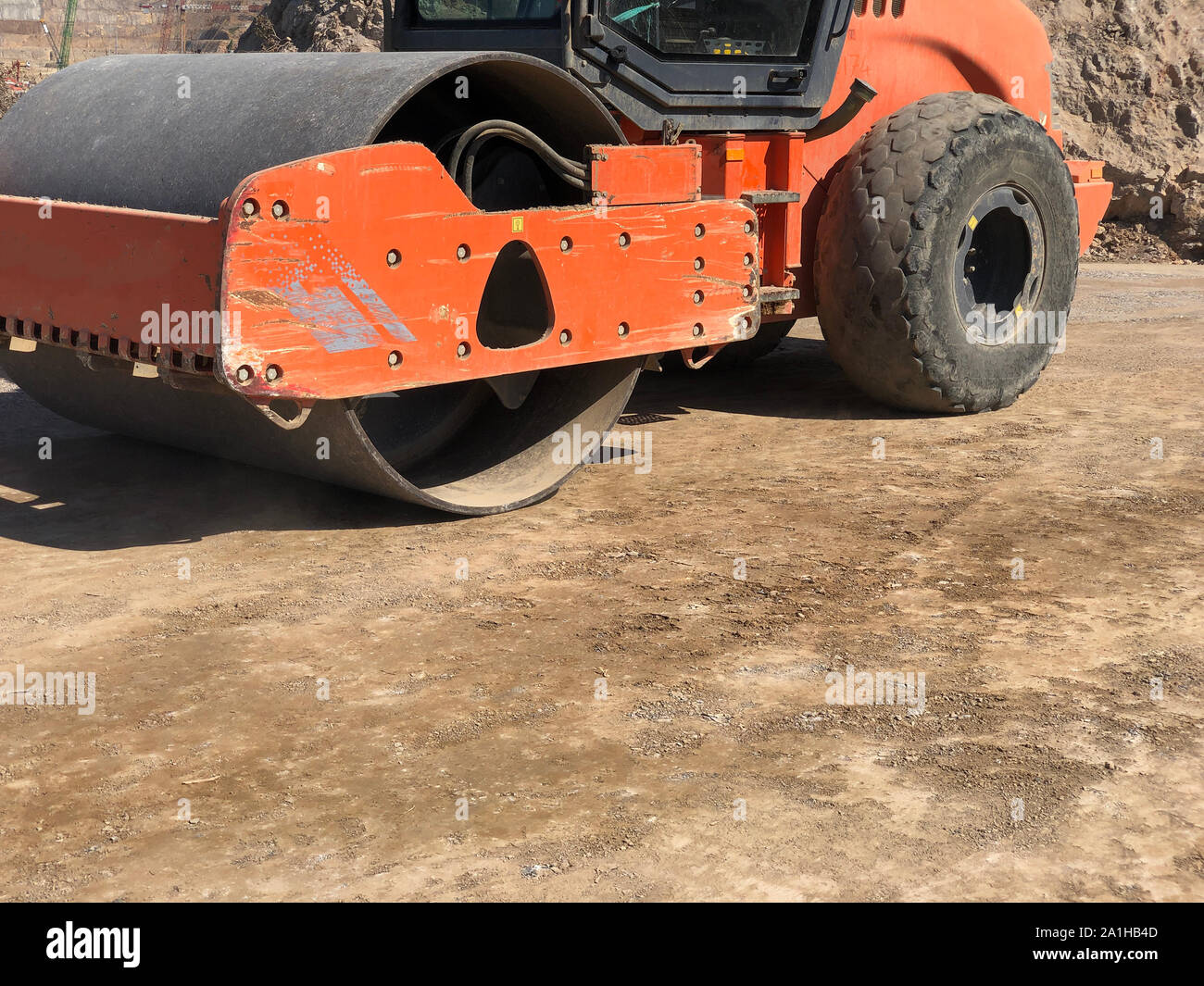 Vibrating roller compresses the soil of a road surface during road construction works. Earthmoving, excavations, digging on the rocky soils. Stock Photo