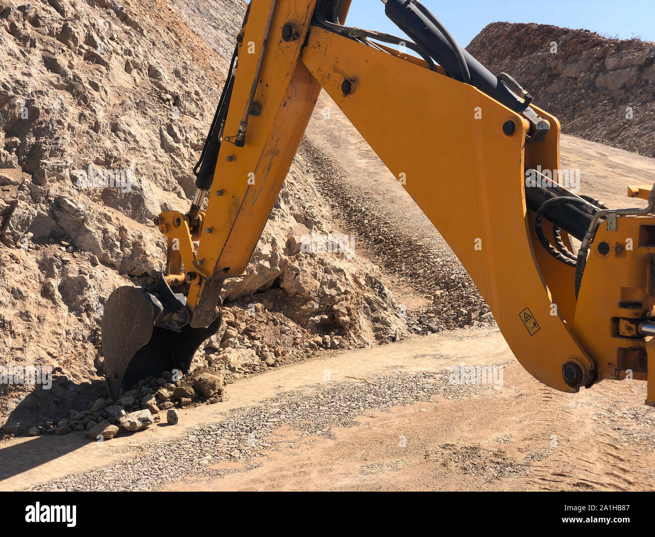 Yellow loader backhoe digs a trench during road construction works